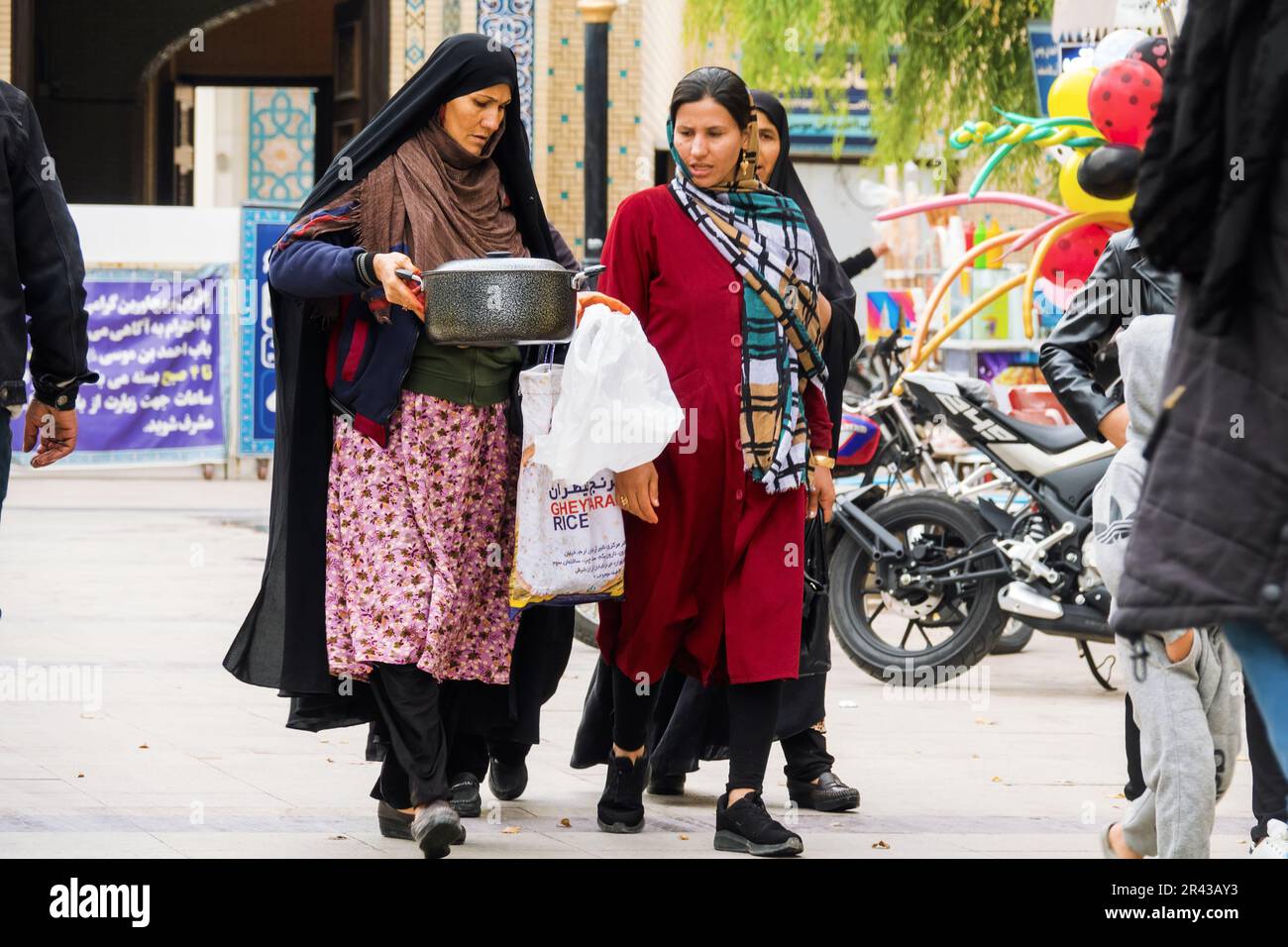 Shiraz, Iran- 31. Dezember 2022: Straßenszene. Frauen haben sich einen neuen Topf auf dem Basar gekauft und diskutieren auf dem Heimweg über seine Vorzüge Stockfoto