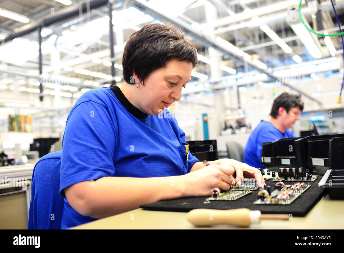 Ältere Frau montiert elektronische Komponenten in einem High-tech-Fabrik Stockfoto