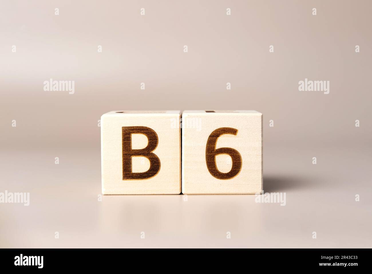 Das Wort B6 über Holzwürfel auf beigefarbenem, neutralem Studiohintergrund. Bereich Kopieren. Geschrieben. Textwörter sind wichtig. Nahrungsergänzungsmittel für die menschliche Gesundheit. Pyridoxin. Es Stockfoto