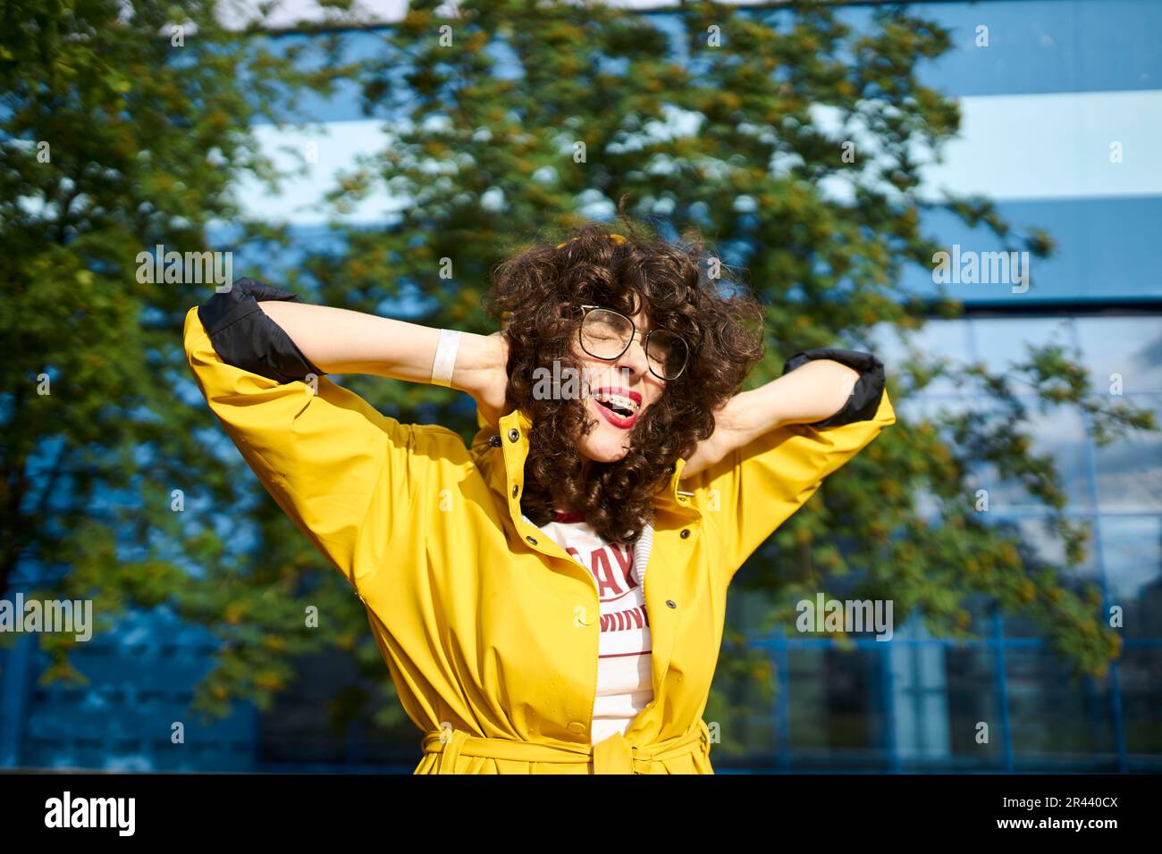 Glückliches Mädchen in einem gelben Regenmantel quietscht vor Freude Stockfoto