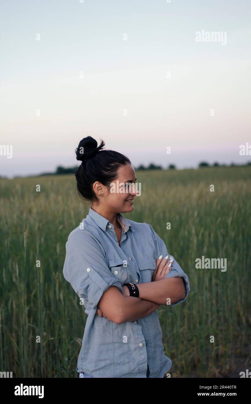 Glückliche Frau, die auf dem Feld steht und lächelt Stockfoto