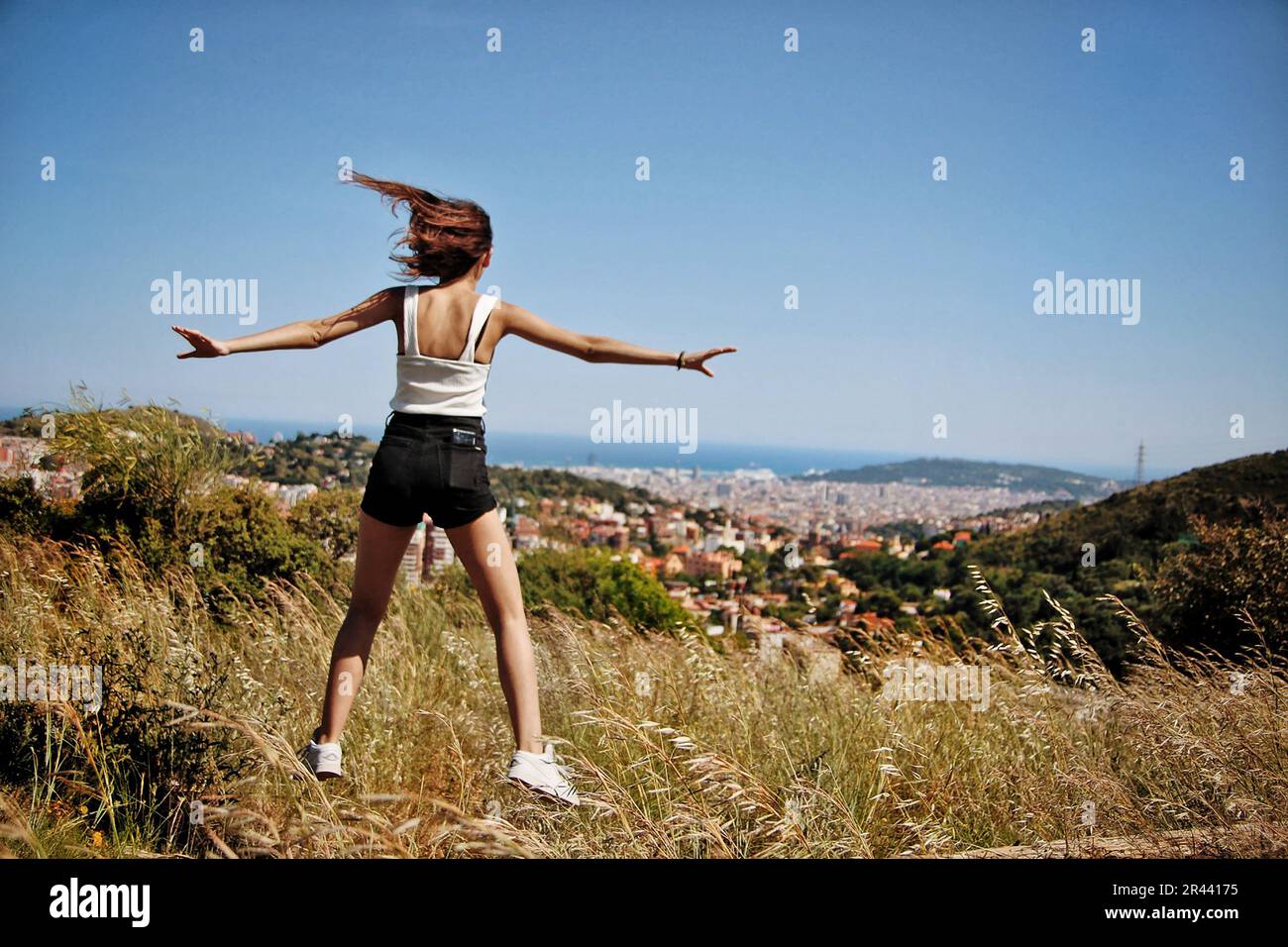 Ein Mädchen in Weiß, das auf den Berg springt. Stockfoto