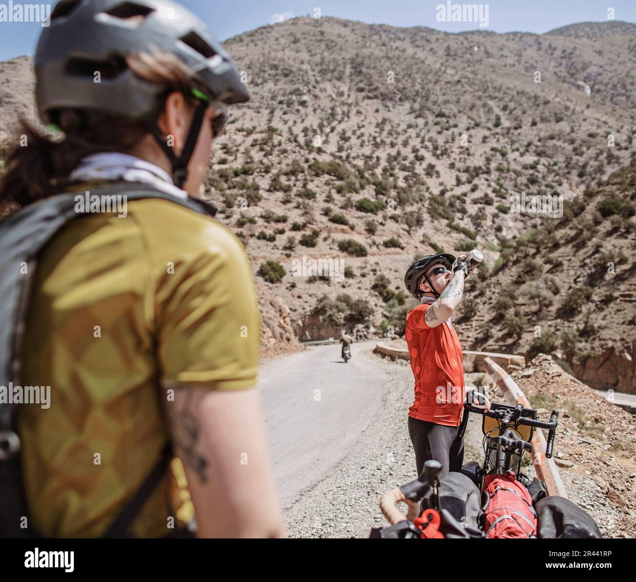 Männlicher Radfahrer trinkt aus seiner Wasserflasche, während er durch Marokko fährt Stockfoto