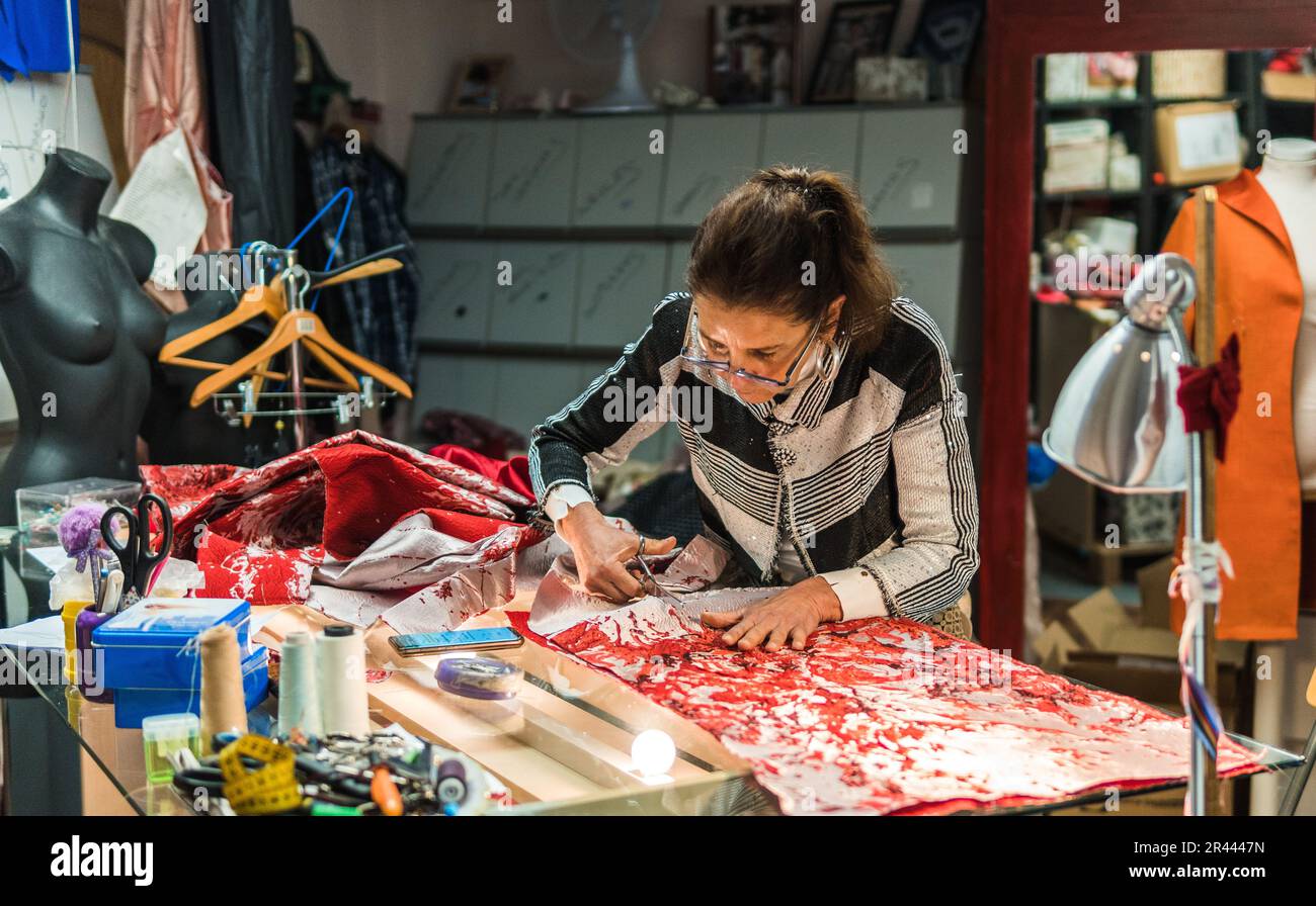 Weibliche Näherin schneidet Stoff in ihrer Nähwerkstatt Stockfoto