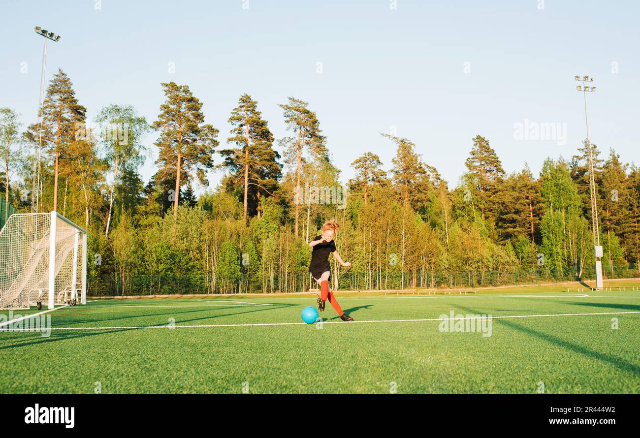 Ein Mädchen, das Football spielt und den Ball auf dem Spielfeld ins Tor tritt Stockfoto