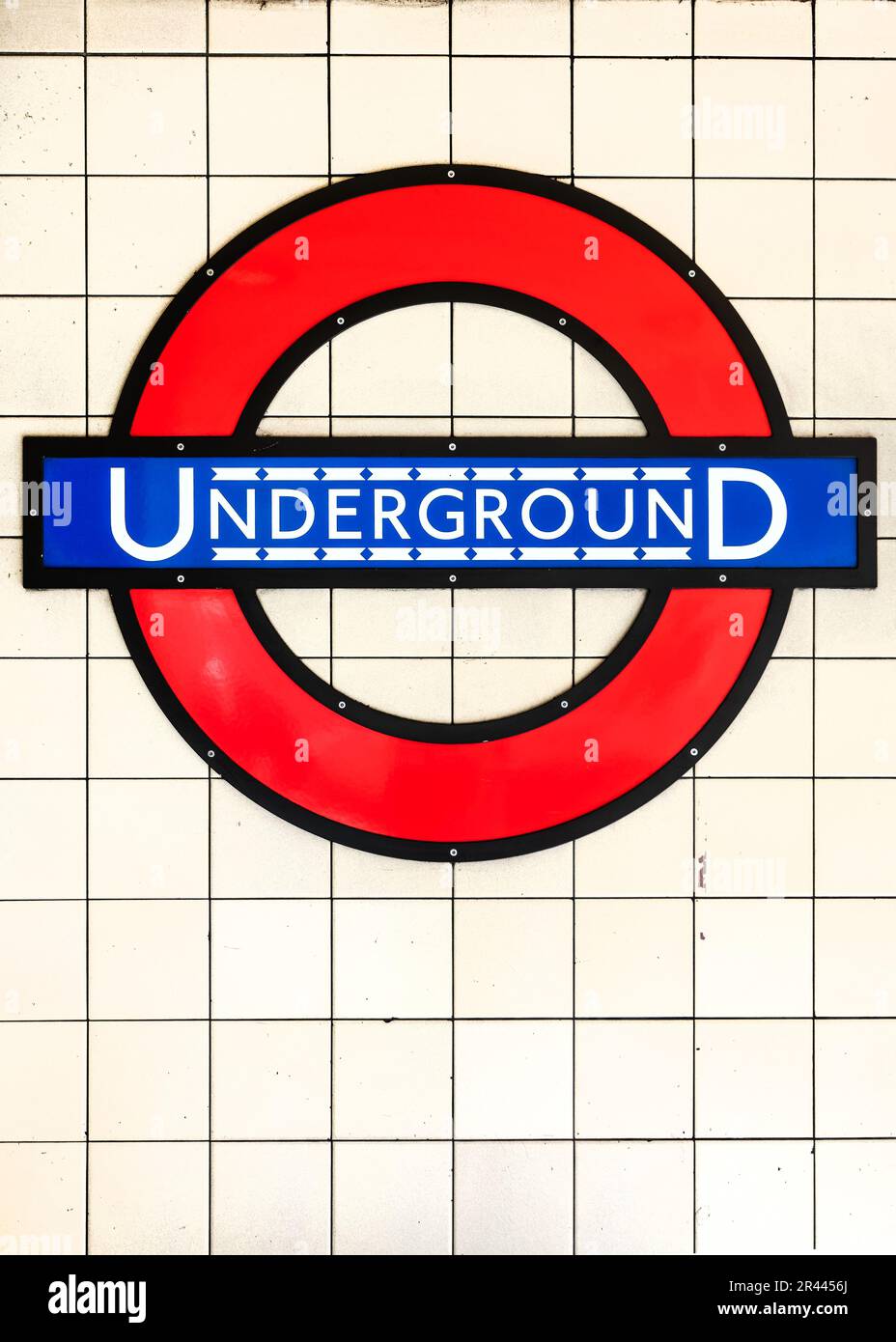 Unterirdisches blaues und rotes Schild auf weißem Hintergrund in einer U-Bahnstation in London, Großbritannien Stockfoto