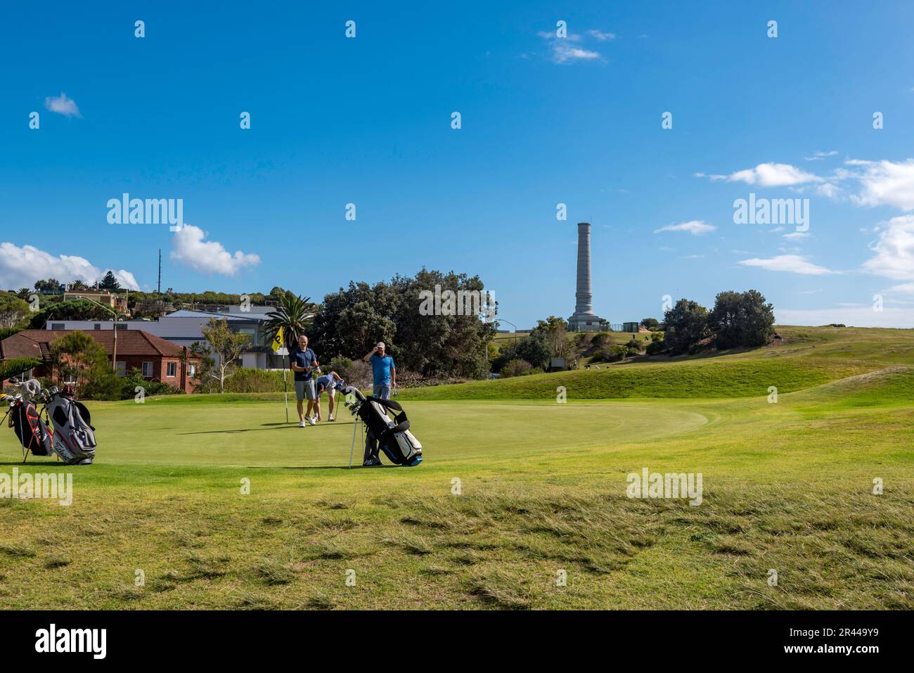 Im Hintergrund befindet sich das zum Kulturerbe gehörende Kanalisationsvent Bondi. Golfspieler schließen auf einem der Grüns im Bondi Golf Club an der Küste in Sydney, Australien, ab Stockfoto