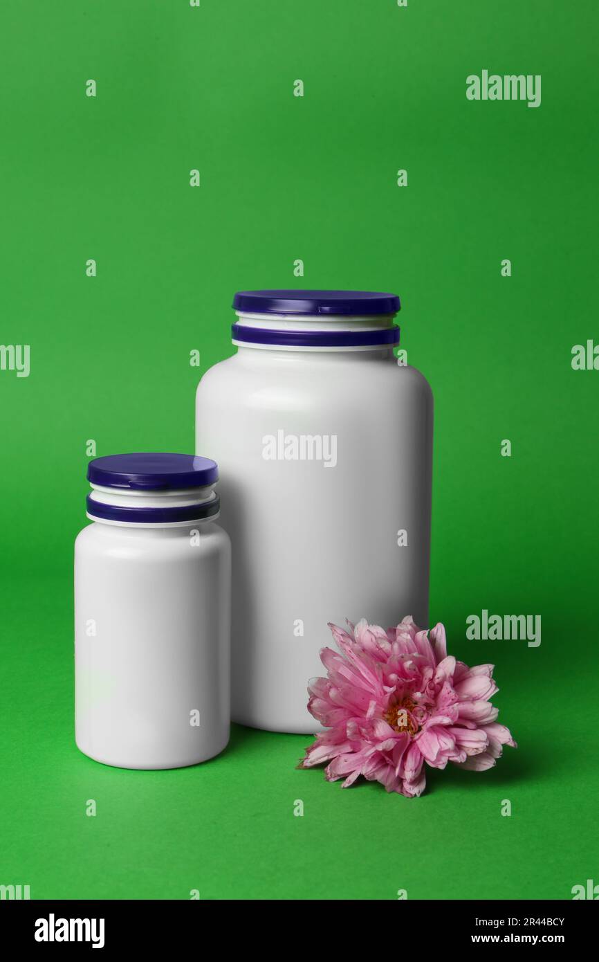 Arzneimittelflaschen und rosa Blume auf grünem Hintergrund. Medikament Stockfoto