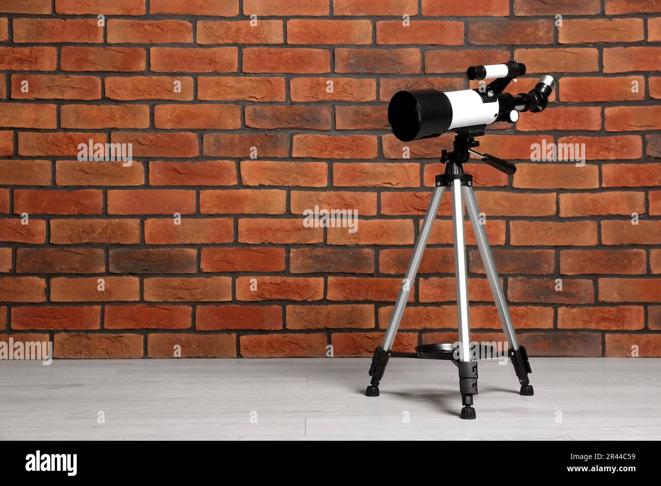 Stativ mit modernem Teleskop nahe der Ziegelwand. Platz für Text Stockfoto