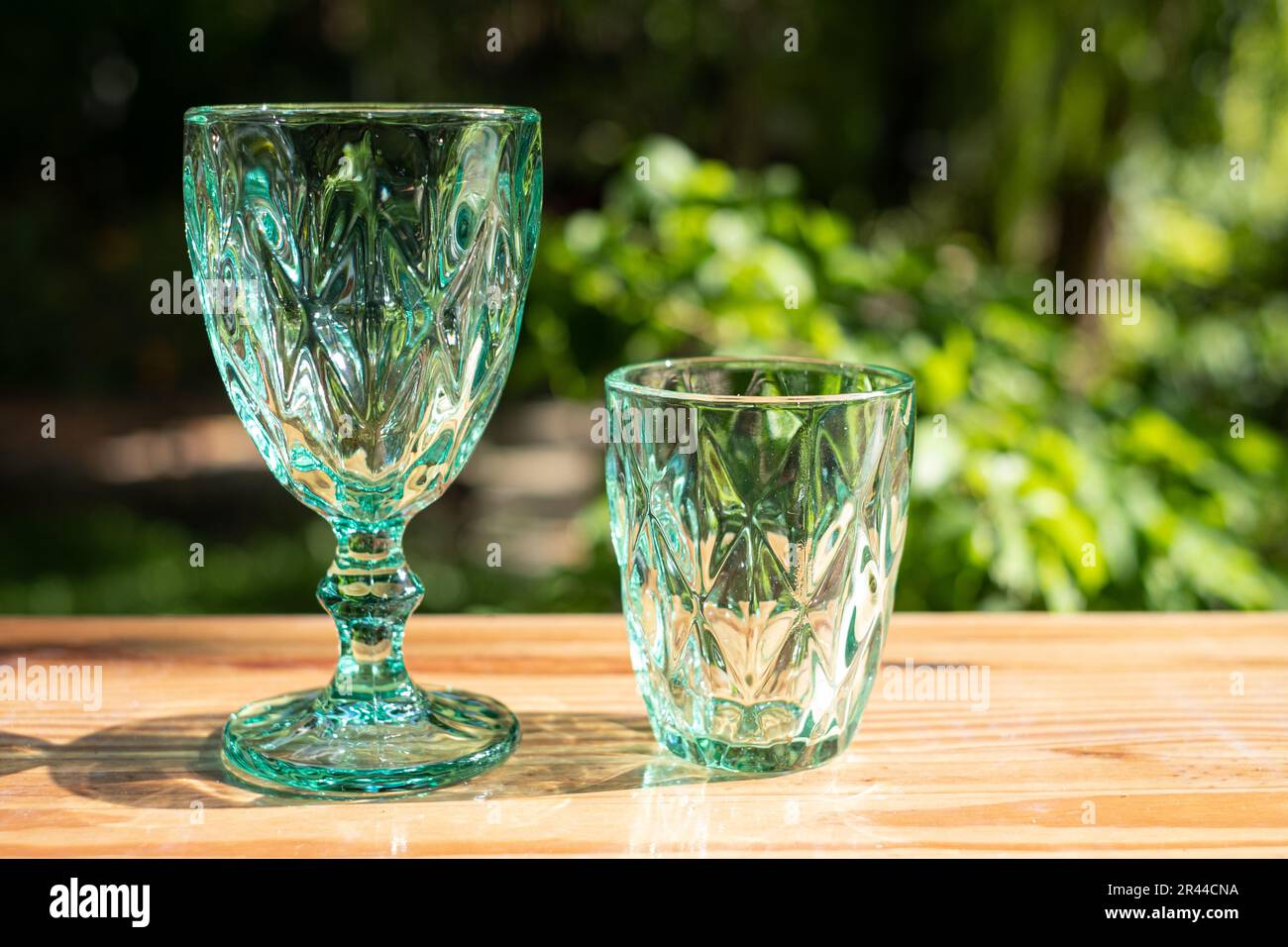 Uranglas oder Saphir-Kristallglas. Grüne Farbtöne Glaswaren klassisches Vintage-Design alte Küchenartikel auf Holztisch Sonnenlicht im Freien reflektiert Stockfoto