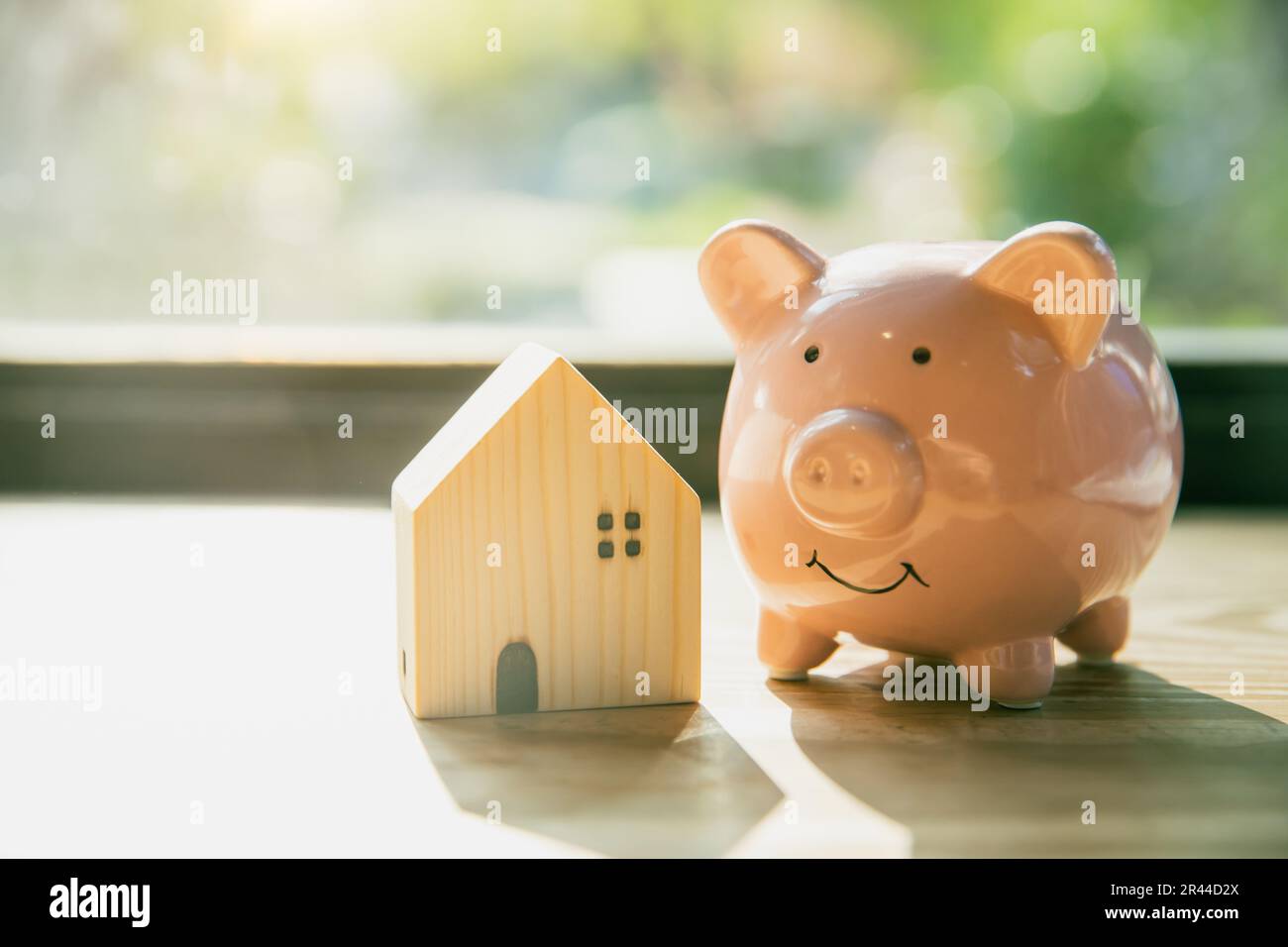 Lächeln Sie Schweinebank mit Haus-Holz-Modell Modell Morgensonnenlicht Hintergrund Stockfoto