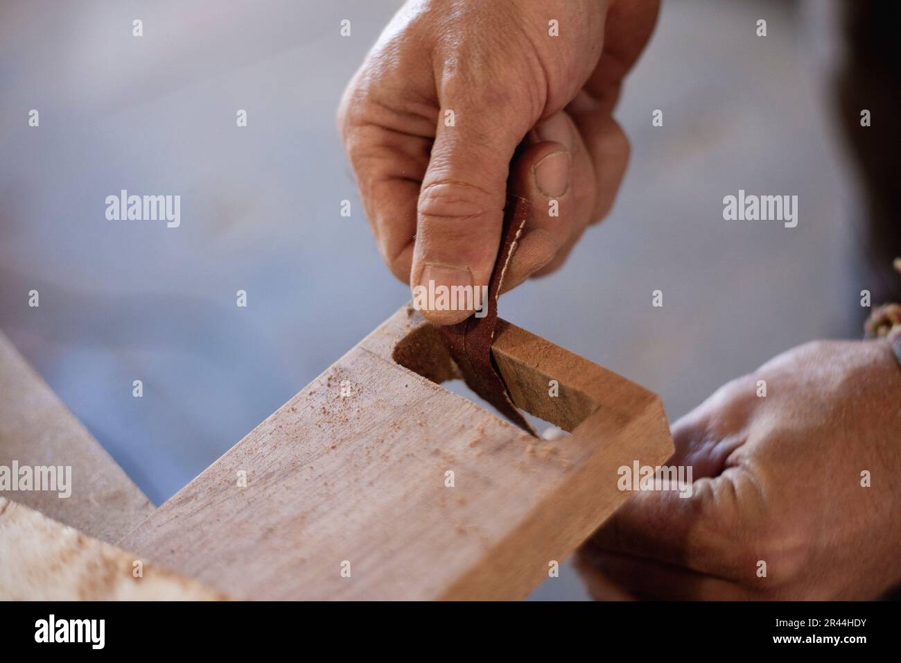 Erfassen der geschickten Hände eines Holzarbeiters beim sorgfältigen Schleifen und Formen des Holzes mit Schleifpapier. Erleben Sie die Kunstfertigkeit in den letzten Phasen von wo Stockfoto