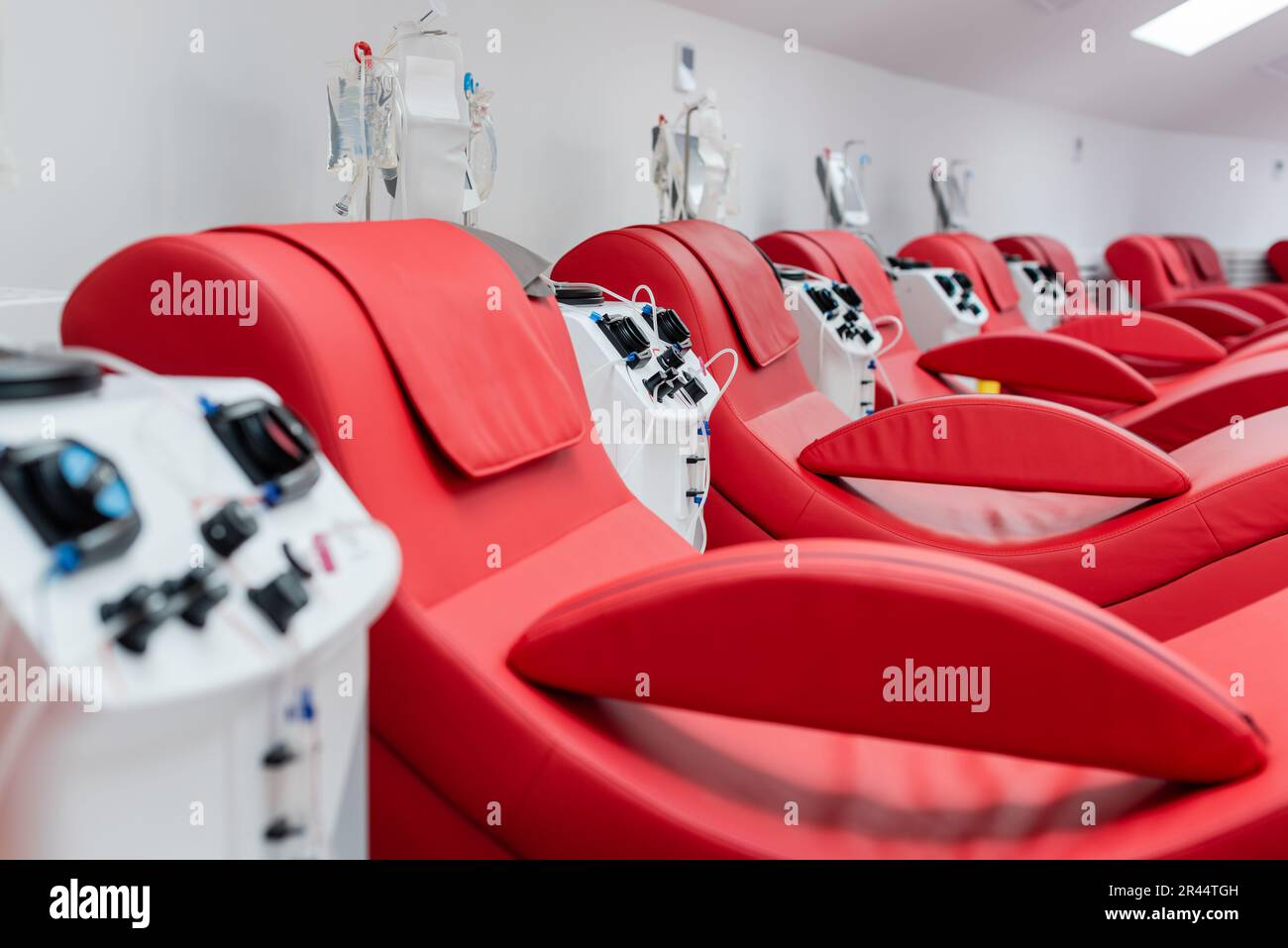 Reihe komfortabler und ergonomischer medizinischer Stühle in der Nähe automatisierter Transfusionsgeräte und Tropfflächen mit Infusionsbeuteln im modernen Blutlabor Stockfoto