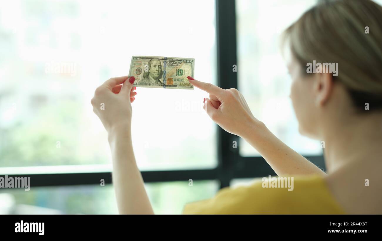 Eine Frau, die Wasserzeichen auf Geld-Dollar vor der Fensterschließung studiert Stockfoto