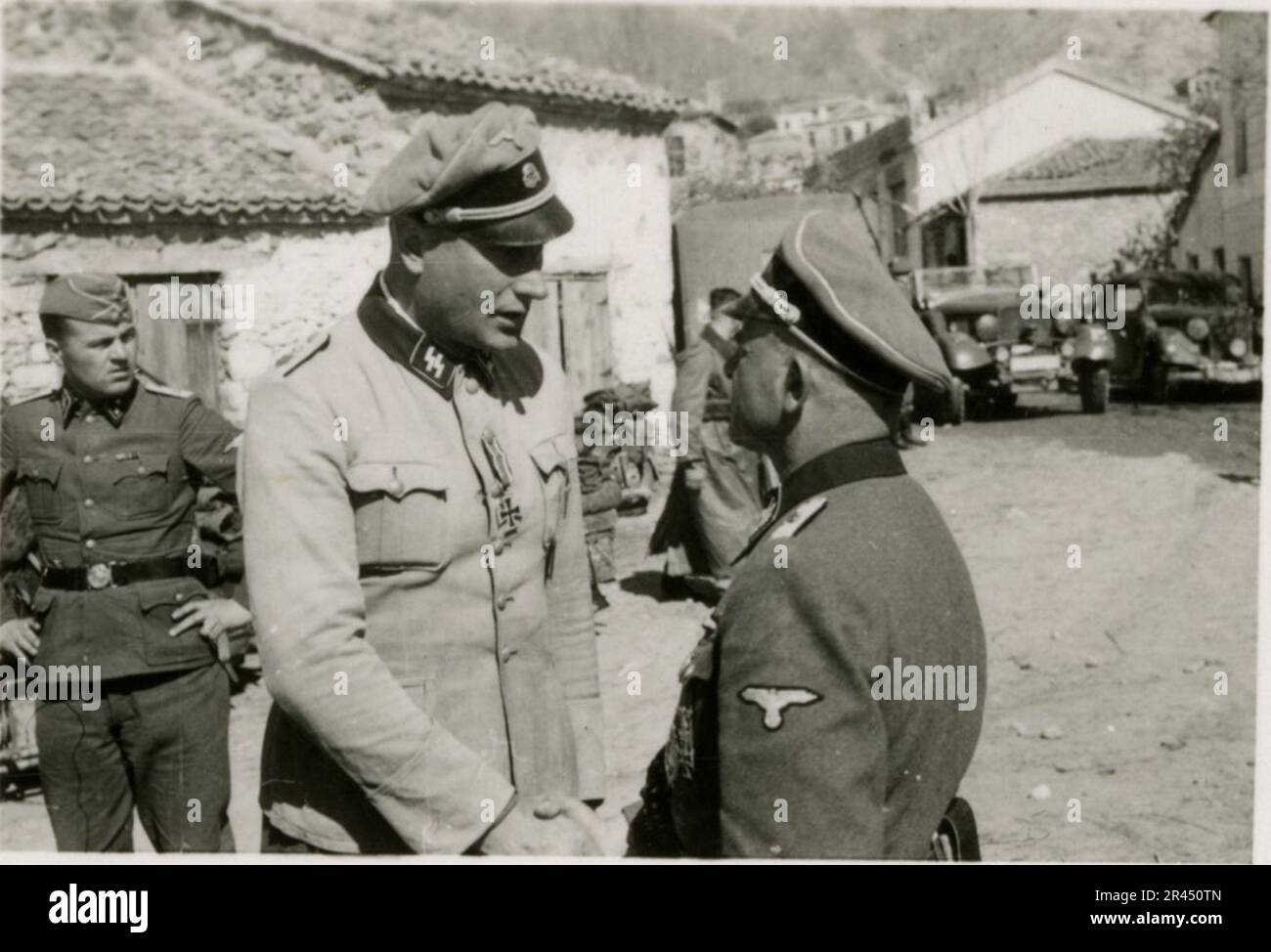 Gunter Alquen (Leibstandarte Adolf Hitler, Griechenland 1941), ein SS-Fotograf, dokumentierte Nazi-Gräueltaten in Griechenland während des Zweiten Weltkriegs Seine Linse erfasste den Schrecken und das Leid, das unschuldigen Zivilisten und Widerstandskämpfern zugefügt wurde. Bilder von Sepp Dietrich, begleitet von Offizieren, aufgenommen in Fotografien neben Soldaten, griechischen Soldaten und Zivilisten, griechischer Landschaft, Gebäuden, Pontonbrücken-Operationen. Zahlreiche Fahrzeuge mit taktischen Symbolen und den Folgen der Zerstörung: Zerstörte Gebäude, Fahrzeuge, Ausrüstung. Artilleriebeschüsse und Szenen, die einen vom Krieg zerrütteten Countr darstellen Stockfoto