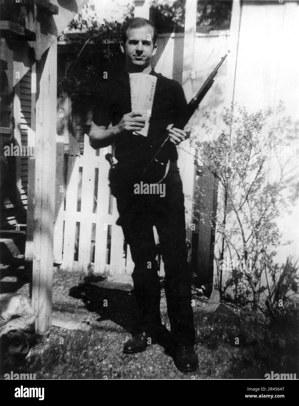 "Hinterhoffoto" von Lee Harvey Oswald, Attentäter der USA Präsident John F. Kennedy hält zwei marxistische Zeitungen, den Militanten und den Arbeiter, und ein Carcano-Gewehr, mit den Markierungen auf dem Gewehr, das nach dem Attentat im Buchlager gefunden wurde. Stockfoto