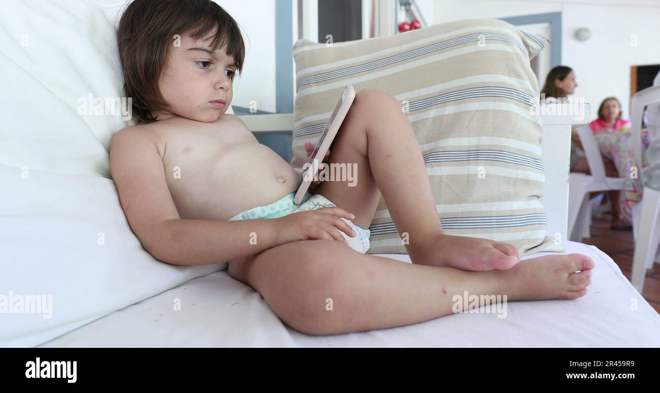 Ein kleines Mädchen, das sich auf dem Smartphone einen Cartoon auf dem Sofa ansieht Stockfoto