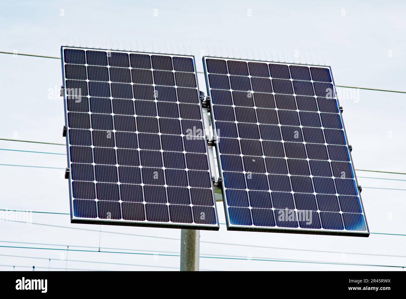 Solarmodul an einem Pol mit elektrischen Kabeln im Hintergrund Stockfoto