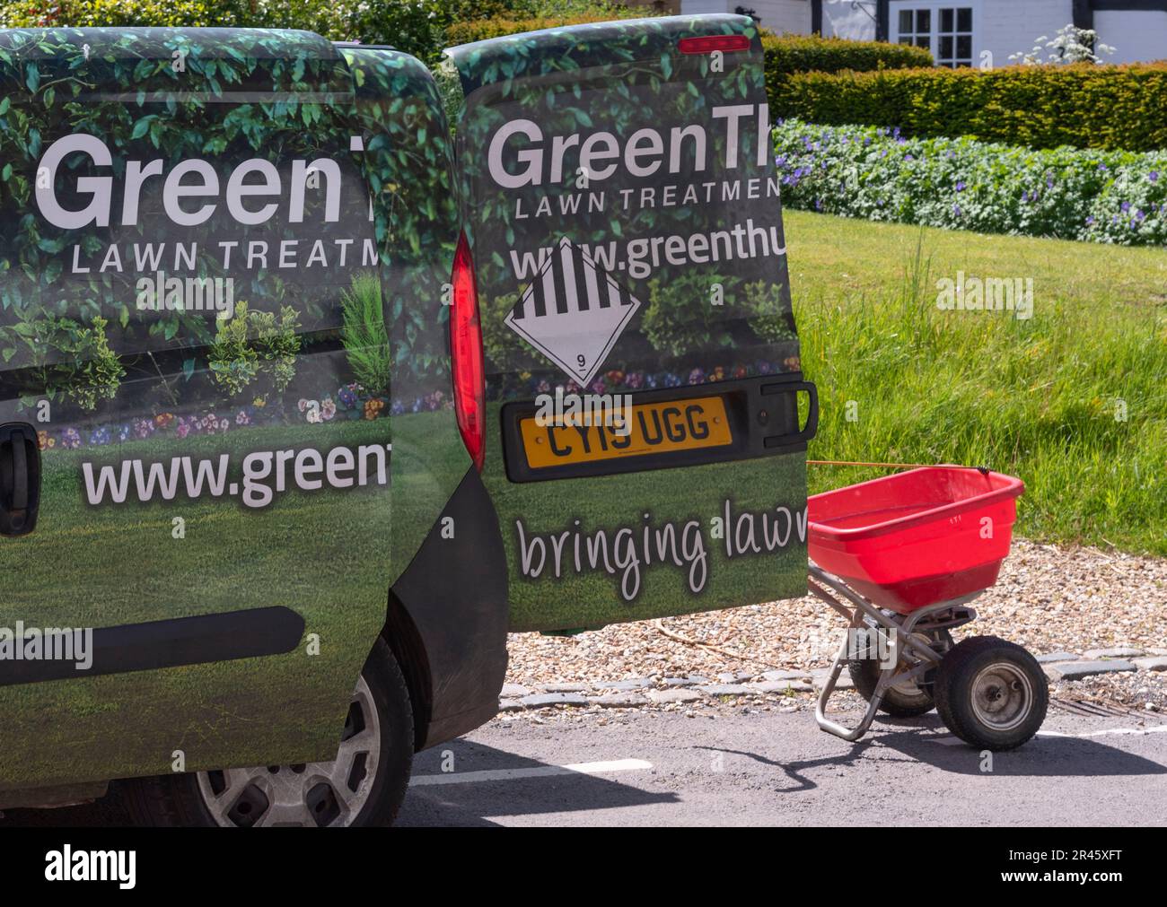Hampshire, England, Großbritannien. 2023. Aufbereitungswagen für Rasen vor Ort mit rotem Streuer zum Abfüllen von Granulat auf das Gras. Stockfoto
