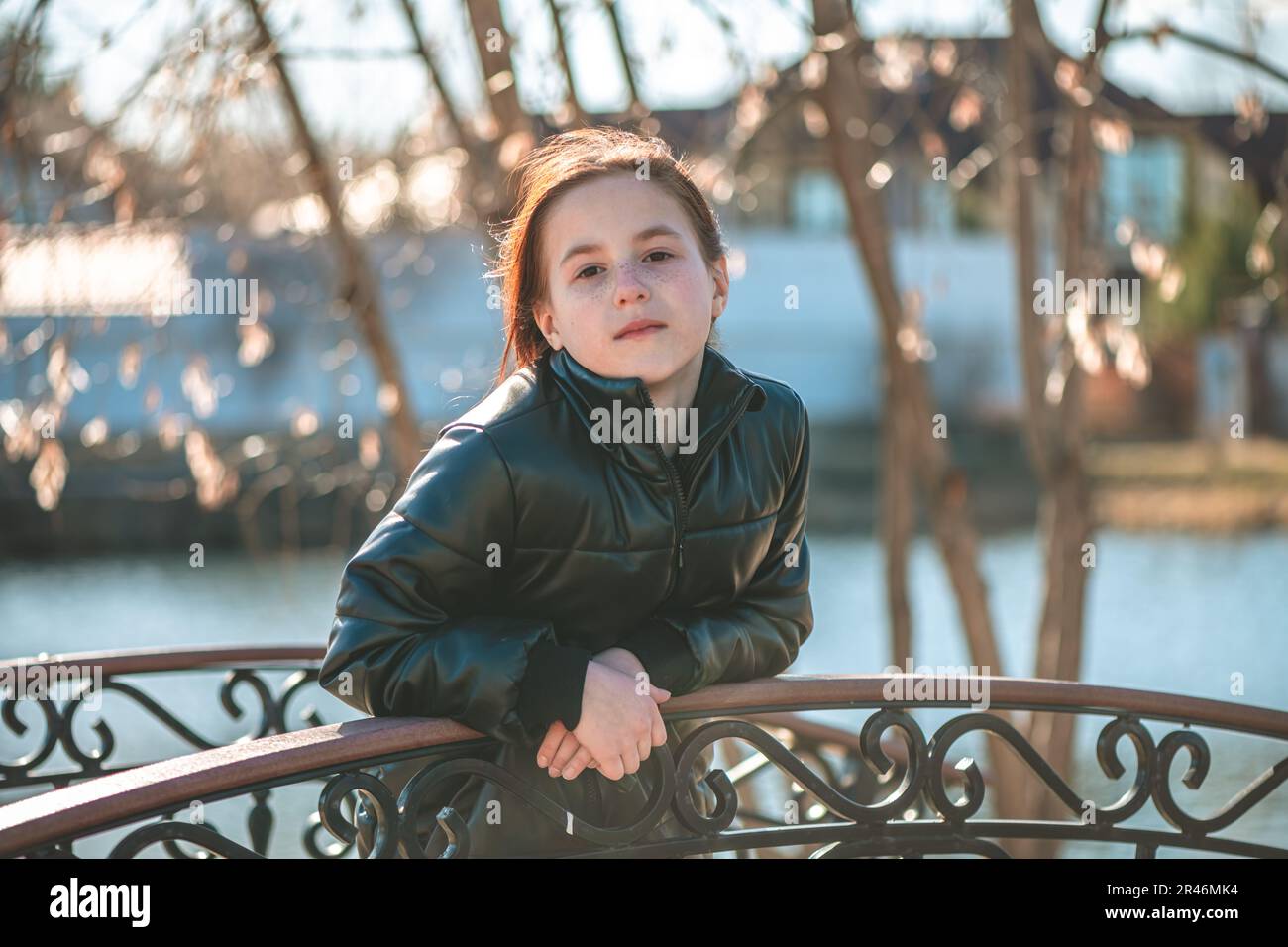 Ein pensives Mädchen im Schulalter steht auf der Brücke und schaut in die Ferne Stockfoto