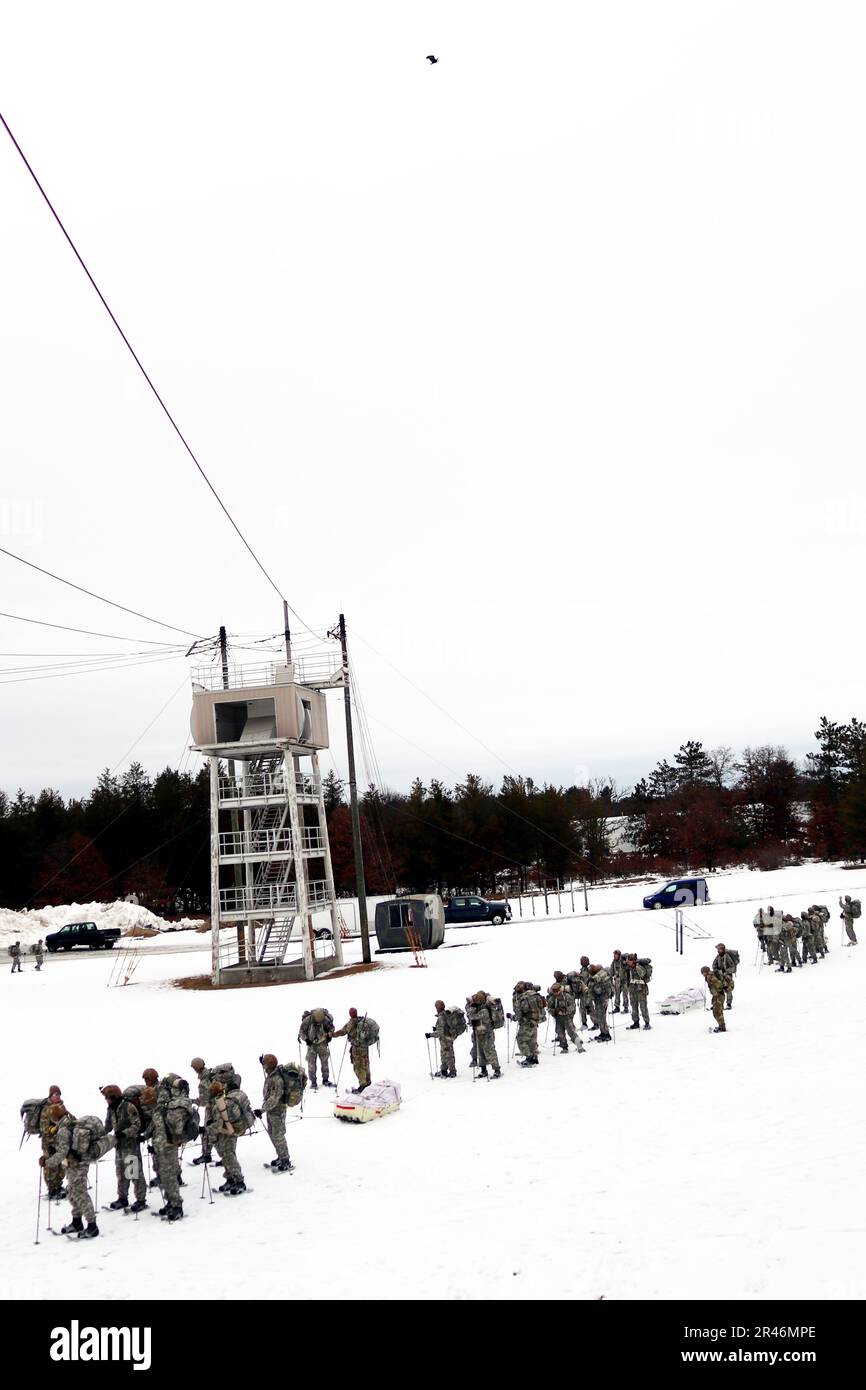 Ein Adler fliegt über den Wolken, während Airmen mit mehreren Einheiten der Air National Guard am 18. Januar 2023 im Rahmen eines 16-tägigen Kurses über Operationen bei kaltem Wetter, der von der Air Force in Fort McCoy, Wisconsin, geleitet wird, die Taktik einer Truppe erlernen, die einen Ahkio-Schlitten zieht. Mehr als 50 Flugzeuge nahmen an der Schulung aus der gesamten Luftwaffe Teil. Neben dem Wissen über die Verwendung von Schneeschuhen und das Bewegen als Truppe über das Gelände, das einen Ahkio-Schlitten in einer Umgebung mit kaltem Wetter zieht, erfuhren die Airmen auch etwas über Unterstände bei kaltem Wetter, Überlebenstechniken, Kleidung für kaltes Wetter und vieles mehr. Fort McCoy hat eine lange Geschichte von Suppo Stockfoto