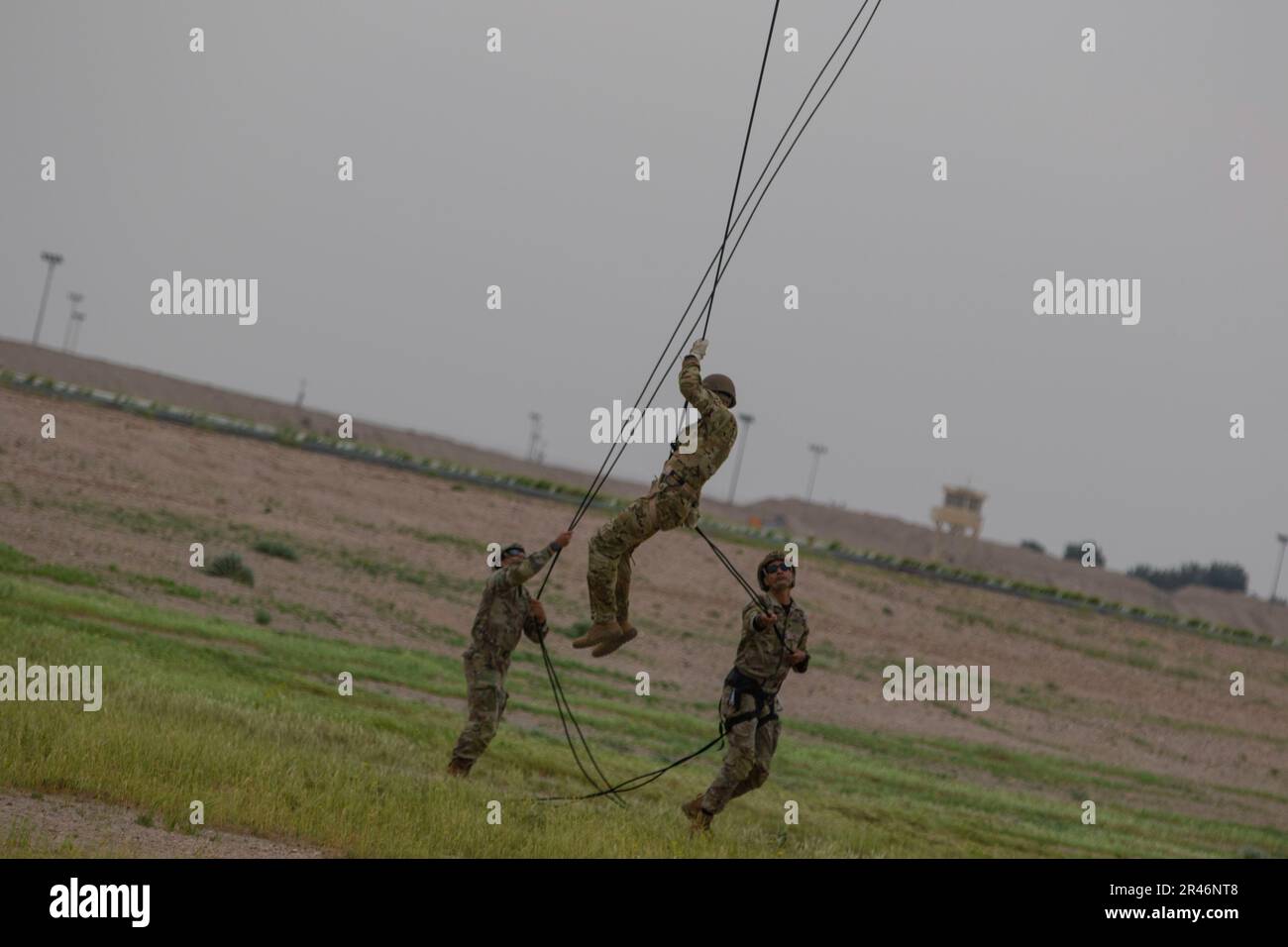 Zwei Soldaten führen einen weiteren Schüler im Rappel Master Course, während er während des Kurses im Camp Buehring, Kuwait, von einem UH-60 Black Hawk absteigt. Abseilmeister sind in der Lage, Abseilarbeiten durchzuführen und zu steuern sowie Inspektionen durchzuführen, um die Sicherheit der Abseilgeräte zu gewährleisten. Stockfoto