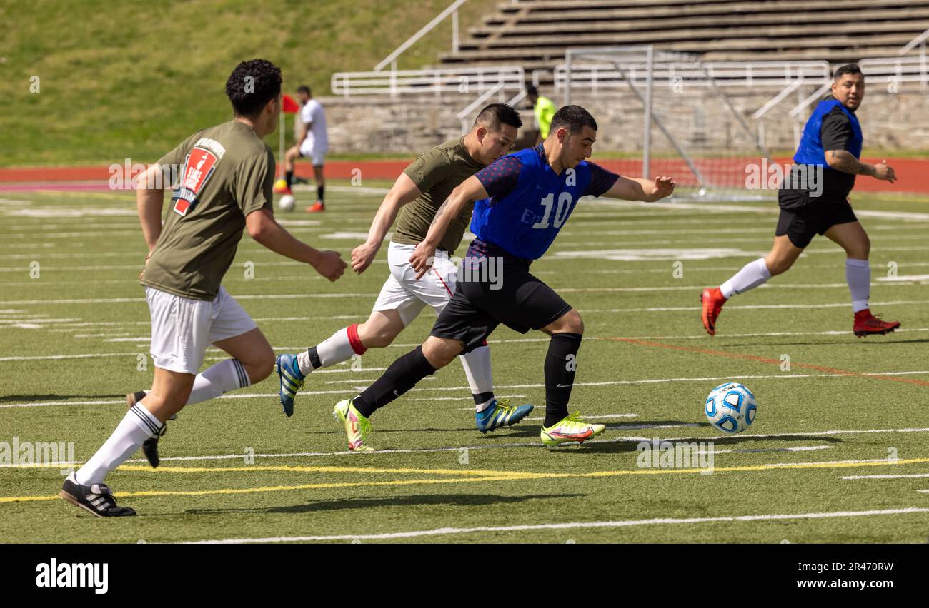 Teilnehmer des Quantico Crossroads Cup, veranstaltet vom Marine Corps Community Services Quantico, verfolgen einen Fußball während eines 7v7 Fußballturniers im Butler Stadium auf der Marine Corps Basis Quantico, Virginia, 1. April 2023. Innermuraler Sport verbessert die individuelle Moral und den Teamgeist und fördert Teamarbeit und Zusammenarbeit durch freundschaftlichen Wettkampf. Stockfoto