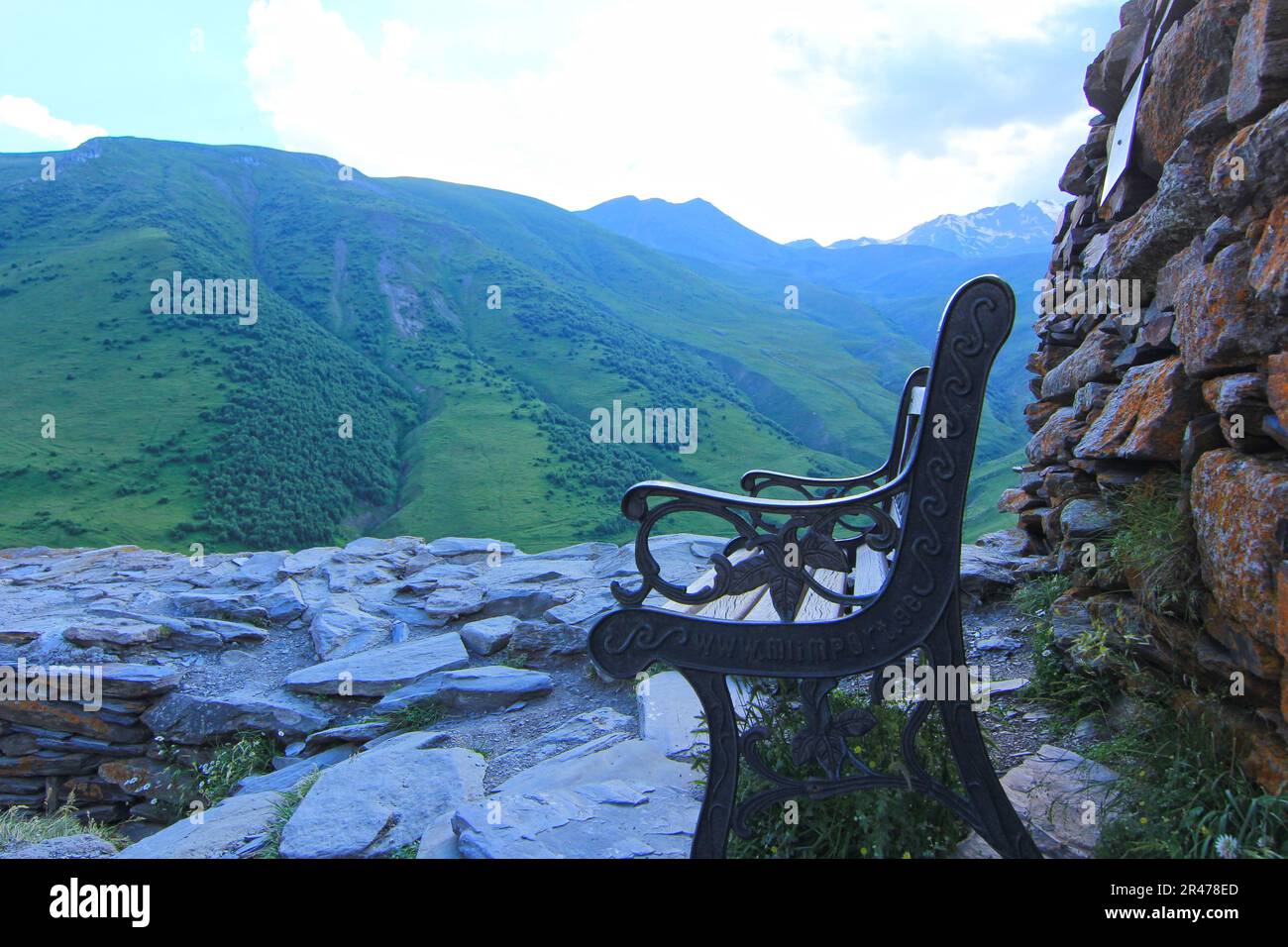 Eine schwarze Holzbank auf einem felsigen Berg mit Blick auf ein wunderschönes Tal darunter Stockfoto