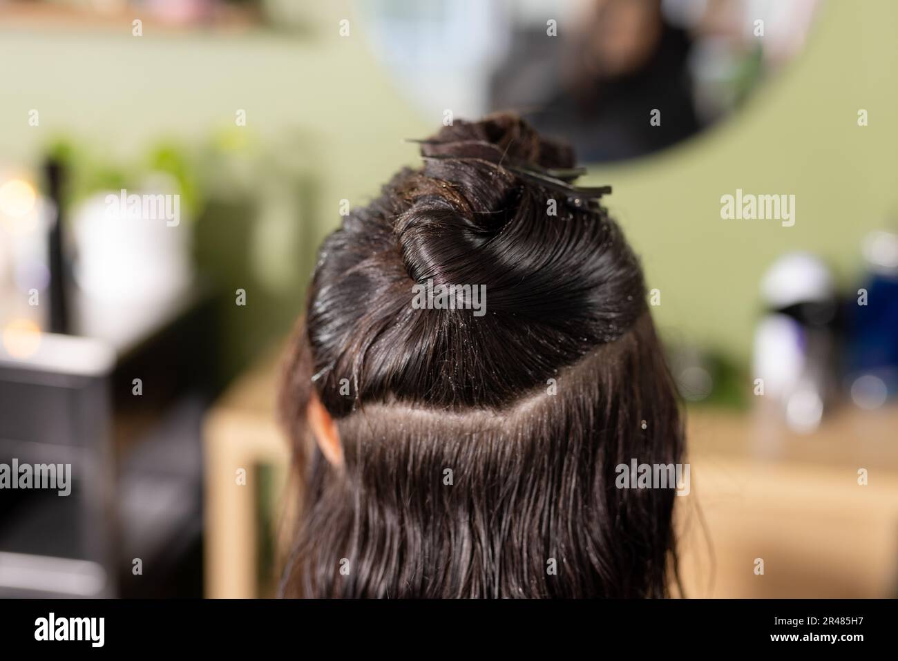 Rückansicht einer weissen Kundin mit nassen Haaren, die vor dem Spiegel im Friseursalon auf den Kopf geschnitten wurden Stockfoto