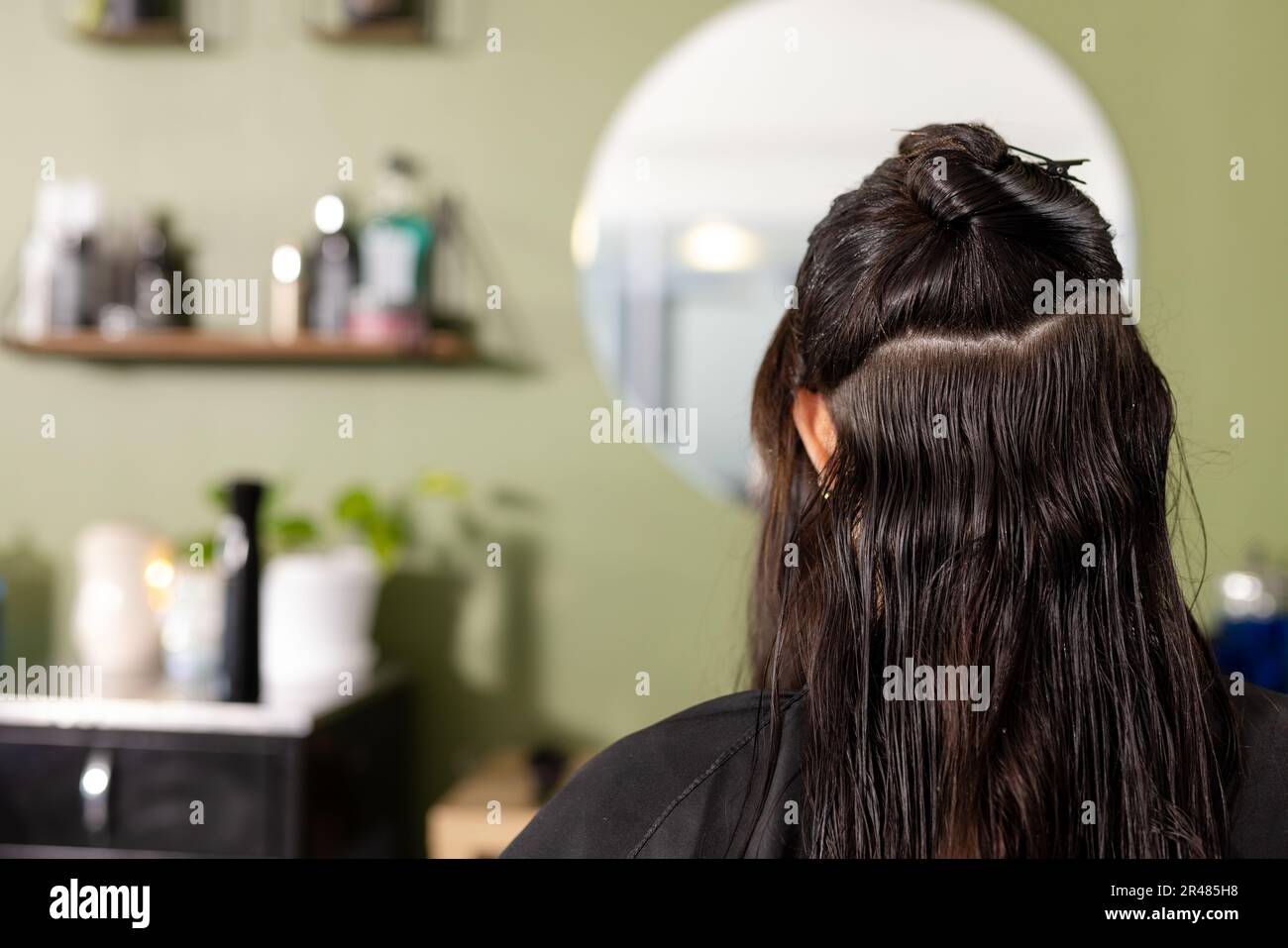 Rückansicht einer weissen Kundin mit nassen Haaren vor dem Spiegel im Friseursalon, Kopierbereich Stockfoto