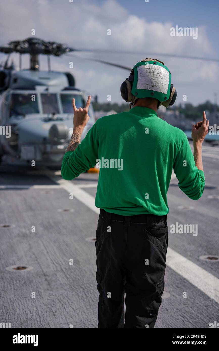 SINGAPUR (16. März 2023) Aviation Electrician’s Mate Airman Daniel Kuriloyoung, der Helicopter Maritime Strike Squadron (HSM) 35 aus Beaverton, Oregon, zugewiesen wurde, kommuniziert mit einem MH-60R SeaHawk, das an HSM-35 angeschlossen ist, auf dem Flugdeck des Kampfschiffs USS Oakland (LCS Naval 24) der Klasse Independence, in Changi Naval Singapur, 16. März 2023. Oakland, Teil der Destroyer-Staffel 7, befindet sich in einem Rotationseinsatz und operiert im US-Flottengebiet 7., um die Interoperabilität mit Alliierten und Partnern zu verbessern und als einsatzbereite Eingreiftruppe zur Unterstützung von a f zu dienen Stockfoto