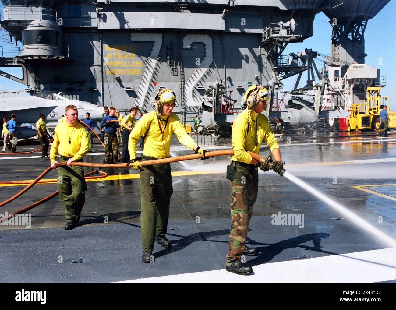 US Navy-Matrosen besprühen Teile der rutschfesten Oberfläche der USS Abraham Lincoln Stockfoto