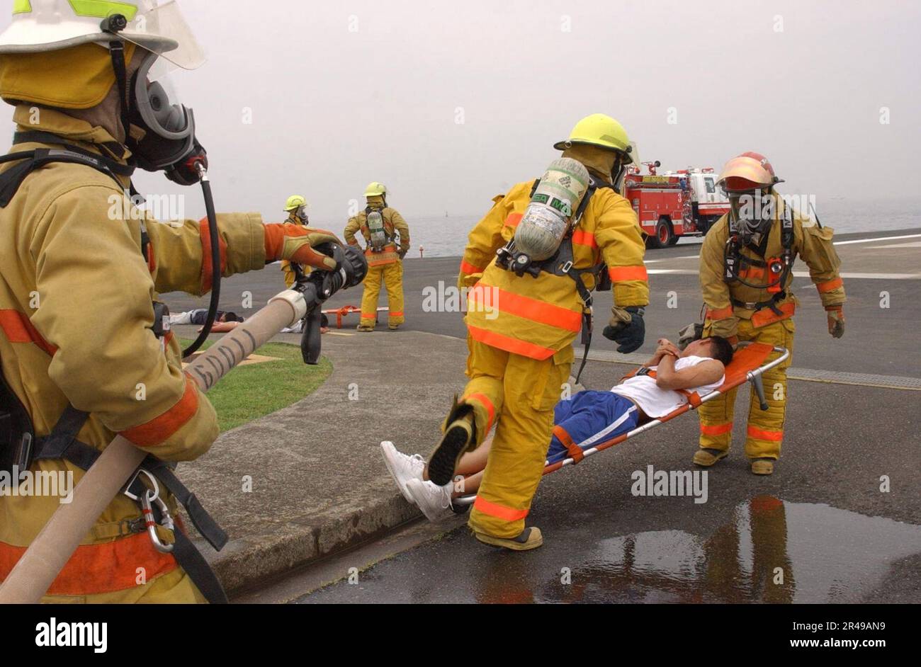 US Navy Feuerwehrleute vom Kommandanten, Naval Forces, Japan Regional Fire Department sind als erste vor Ort, um simulierten Verletzten während einer Hubschrauberabsturzübung zu helfen Stockfoto