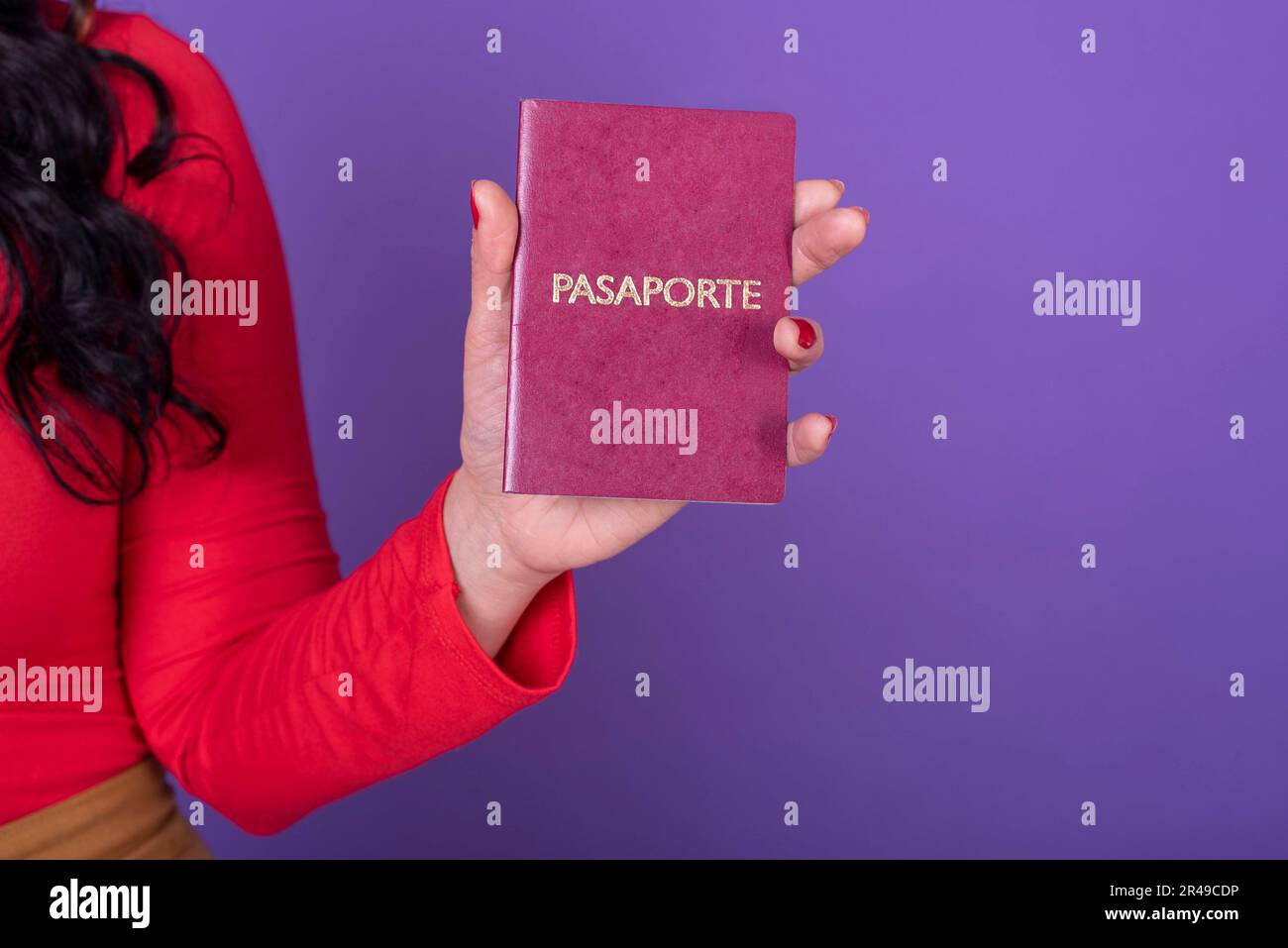 Weibliche Hand, die eine PASAPORTE auf violettem Hintergrund hält. Stockfoto