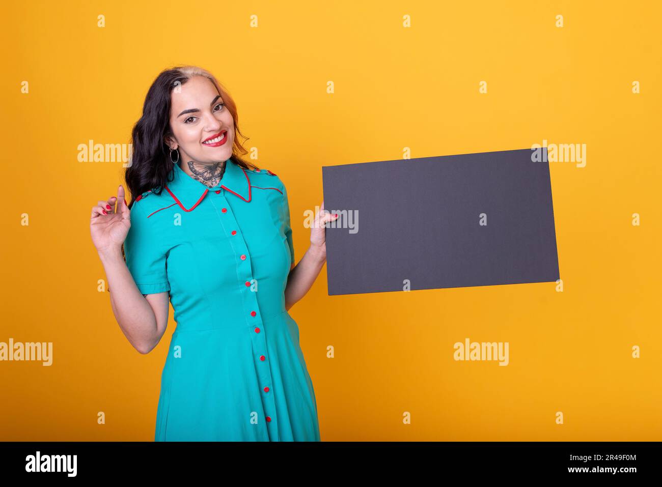 Schöne Frau mit einem leeren Schild vor gelbem Hintergrund Stockfoto