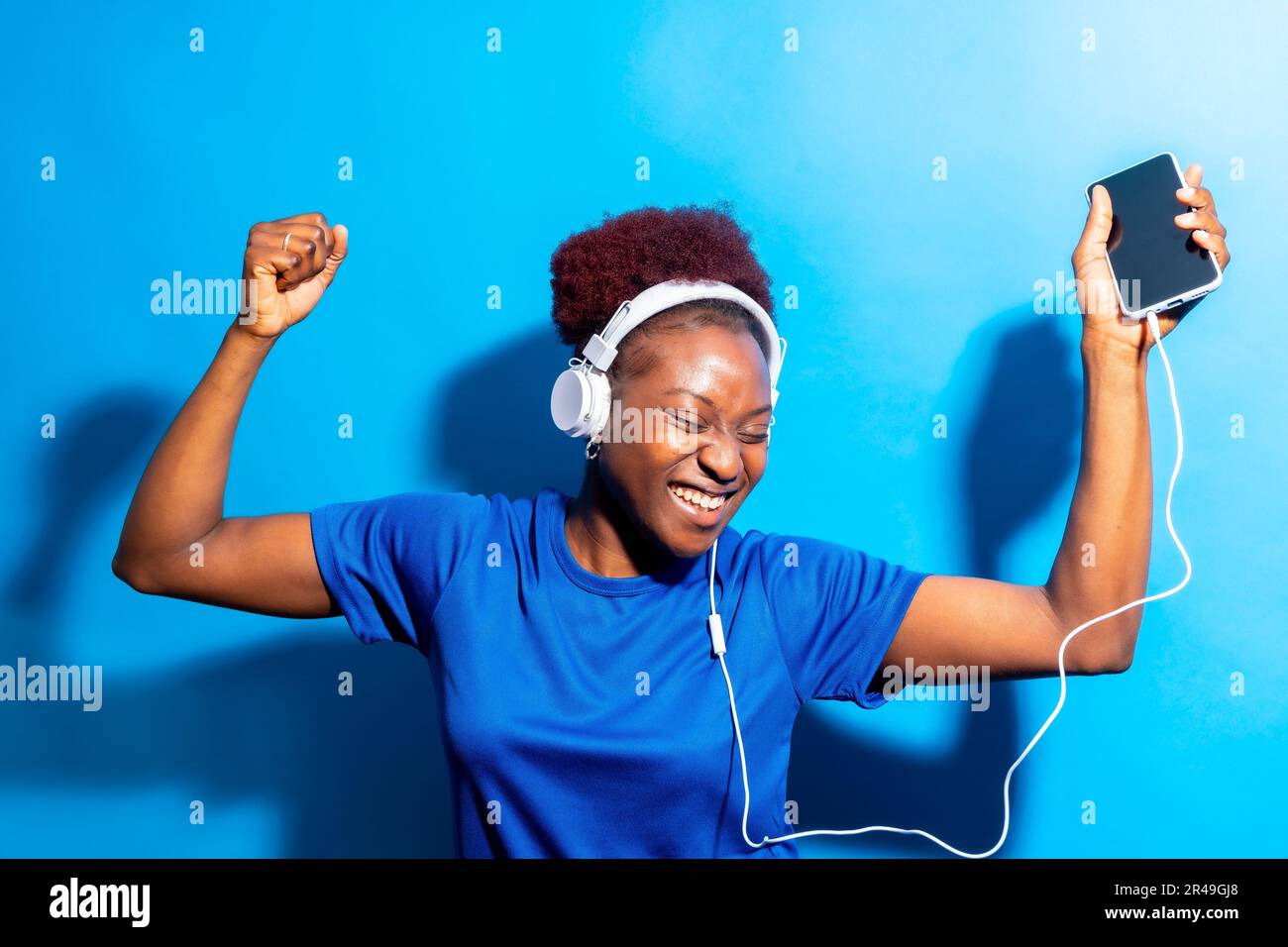 Ein Porträt einer jungen, fröhlichen schwarzen Frau, die Musik mit Kopfhörern hört Stockfoto