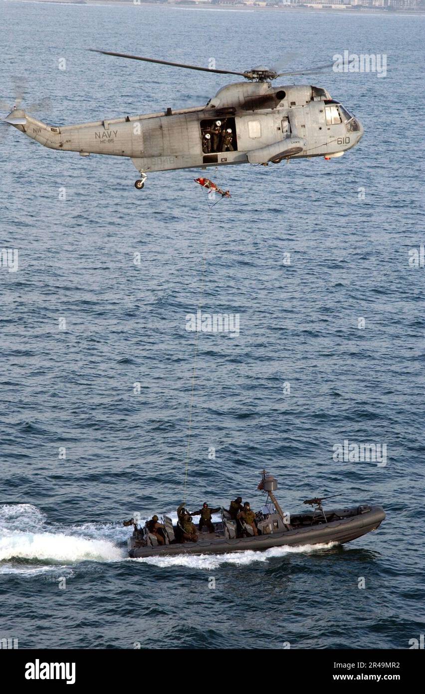 US Navy ein SH-3 Sea King Helikopter, der dem Golden Gators of Helicopter Combat Support Squadron Acht fünf (HC-85) zugeteilt wurde, führt Such- und Rettungsübungen mit Spezialboot Einheit 12 (SBU-12) durch. Stockfoto
