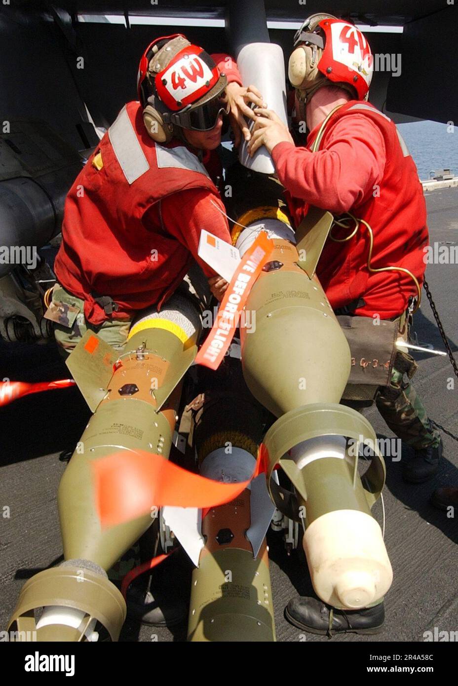 US Navy Aviation Ordnancemen, die den Sunliners des Strike Fighter Squadron Acht Eins (VFA-81) zugeteilt sind, laden eine geführte Bombeneinheit (GBU-12) auf eine F-A-18C Hornet an Bord der USS John F. Kennedy (CV 67) Stockfoto