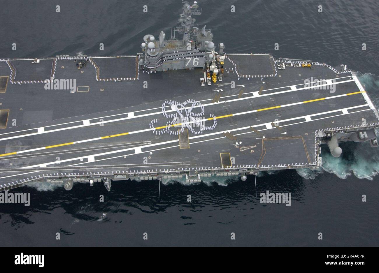 US Navy-Matrosen in weißen Sommeruniformen versammeln sich auf dem Flugdeck an Bord der USS Ronald Reagan (CVN 76) und bilden das Doppel-R-Logbuch des Schiffs zu Ehren des ehemaligen Präsidenten Ronald Reagan Stockfoto