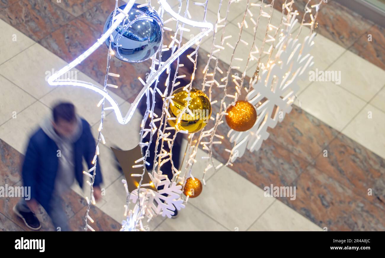 Die Leute laufen unter der Weihnachtsdekoration, die in der Flughafenhalle hängt Stockfoto