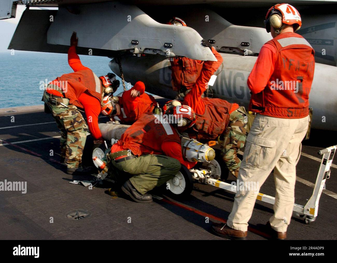 US Navy Aviation Ordnancemen, die den Gunslingers der Streikkämpfer-Staffel eins Null fünf (VFA-105) zugeteilt sind, laden eine 500 kg schwere lasergesteuerte Bombe (GBU-12) auf eine F-A-18 Hornet Stockfoto