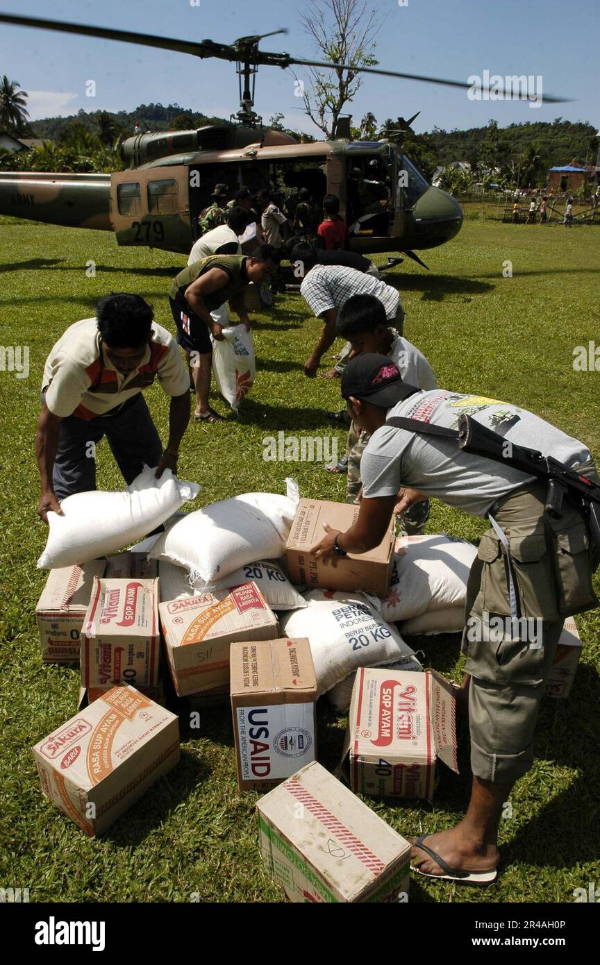 Indonesische US Navy-Staatsangehörige entladen Vorräte aus einem ausländischen Militärhubschrauber UH-1 Irokois in Lamno, Sumatra, Indonesien Stockfoto