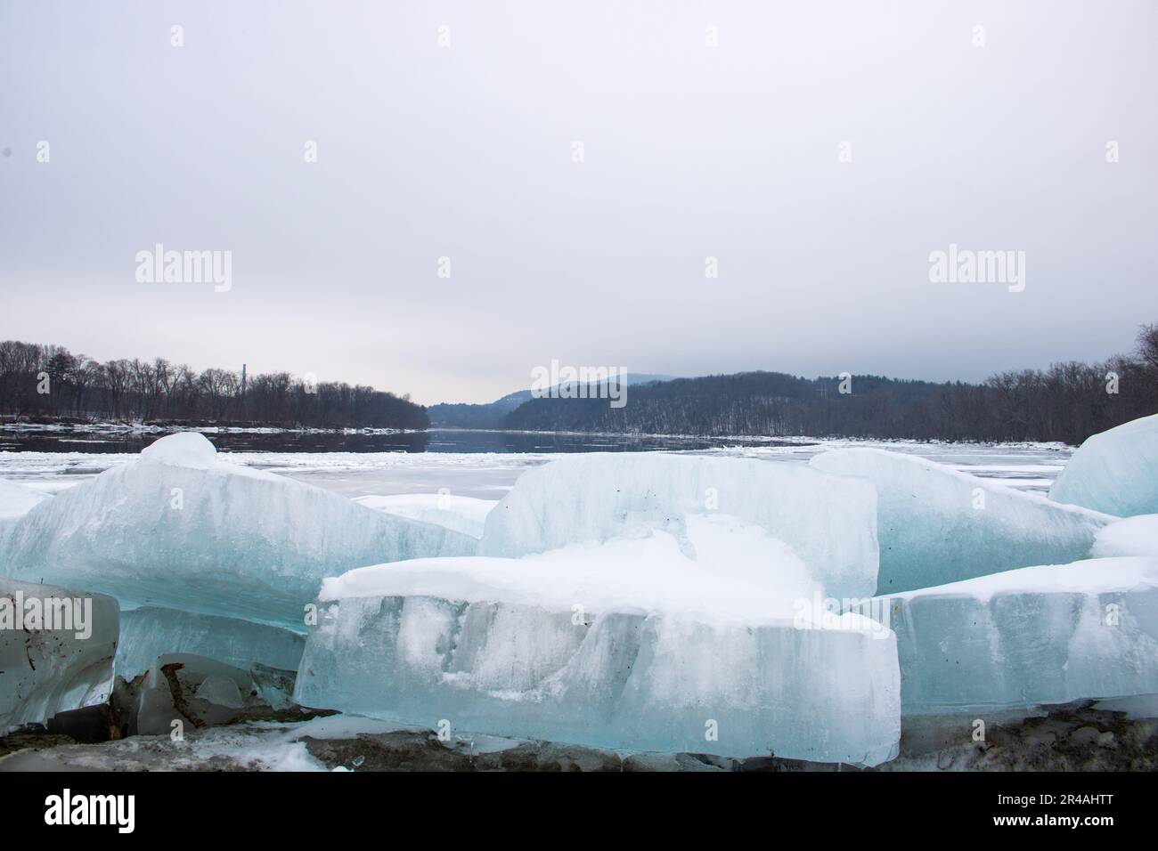 Eine atemberaubende Landschaft mit majestätischen blauen Eisbergen, die über einem ruhigen Gewässer mit einem Hintergrund aus unberührtem weißem Schnee ragen Stockfoto