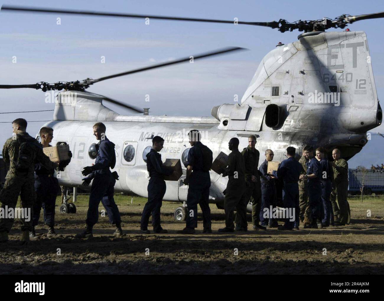 US Navy USA Navy und USA Mitarbeiter des Marine Corps einer Arbeitsgruppe, während sie Nahrung in einen wartenden CH-46 Sea Knight Hubschrauber verladen, der dem Marine Medium Helicopter Squadron 262 (HMM-262) am Sultan gehört Stockfoto