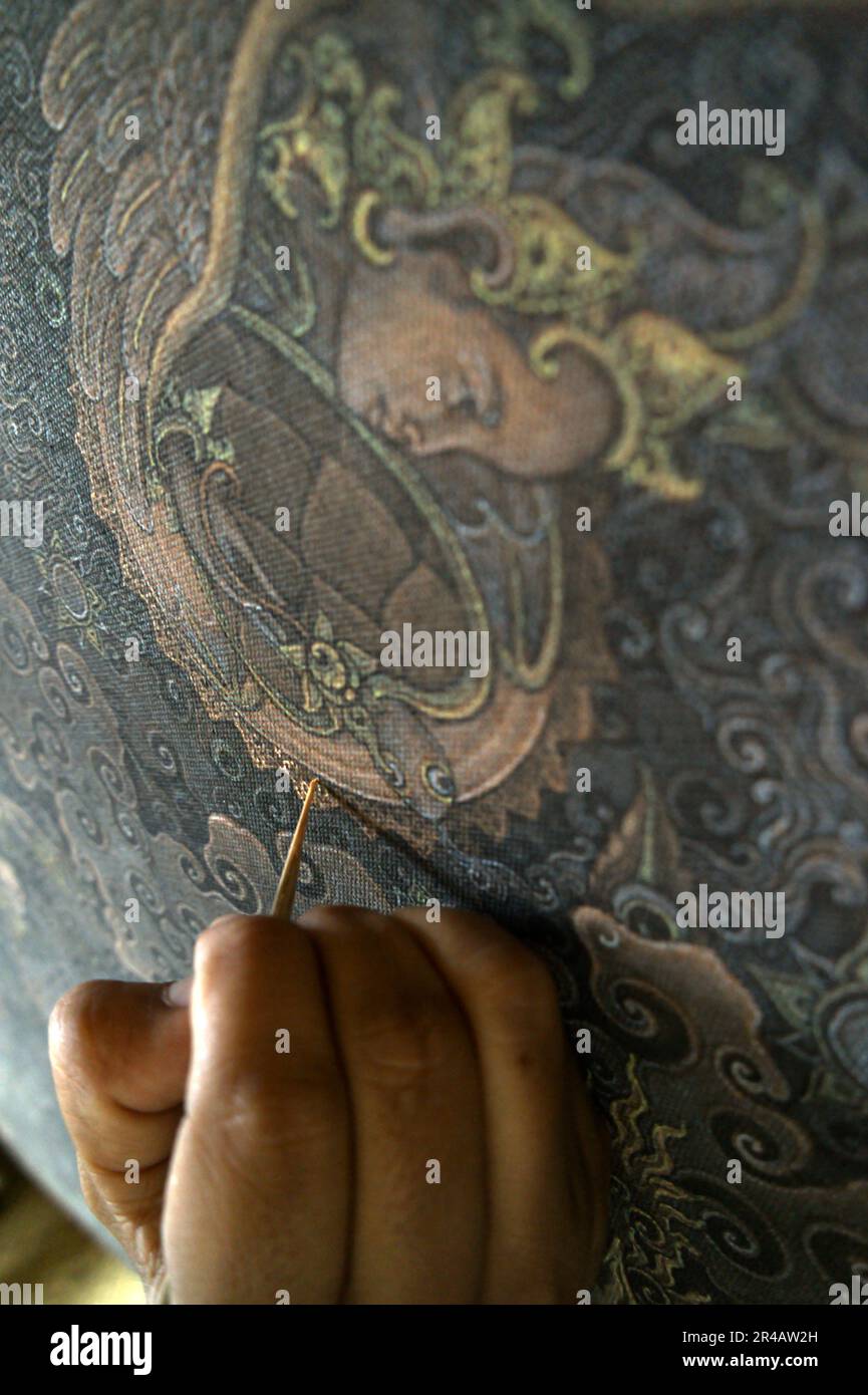 Ein Maler arbeitet an einem Gemälde in Tebesaya (Tebasaya), einem Gebiet, das in der balinesischen Kunstwelt für seine Rolle und seinen Beitrag im „Tebesaya-Malstil“ und in der „Ubud School of painting“ in Ubud, Gianyar, Bali, Indonesien, bekannt ist. Stockfoto