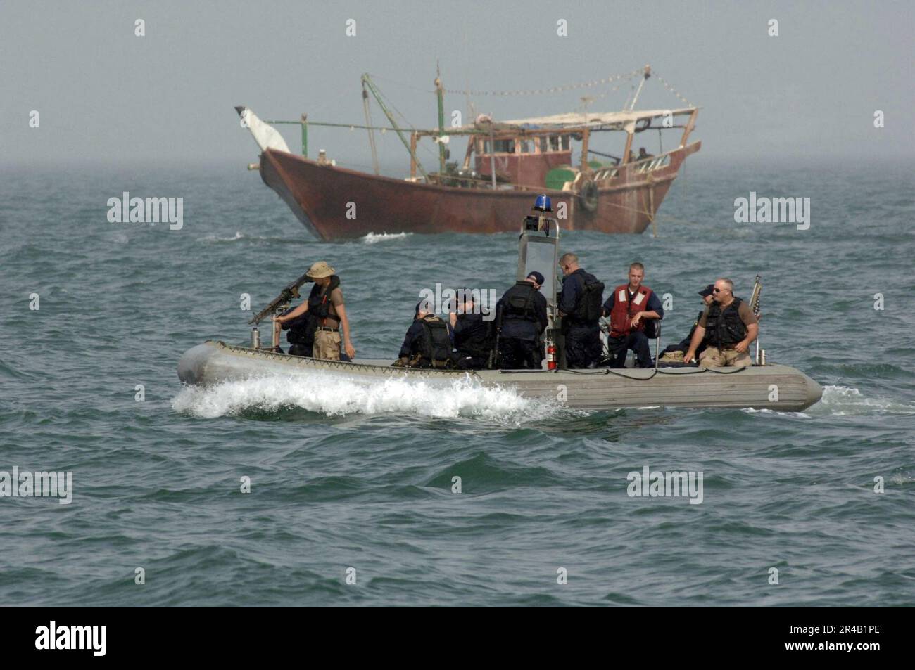 US Navy mit einer Dau im Hintergrund begeben sich Seeleute, die dem Küstenpatrouillenschiff USS Chinook (PC 9) zugeteilt sind, durch die Gewässer um die irakischen Ölterminals zur Unterstützung der maritimen Sicherheitsoperati. Stockfoto