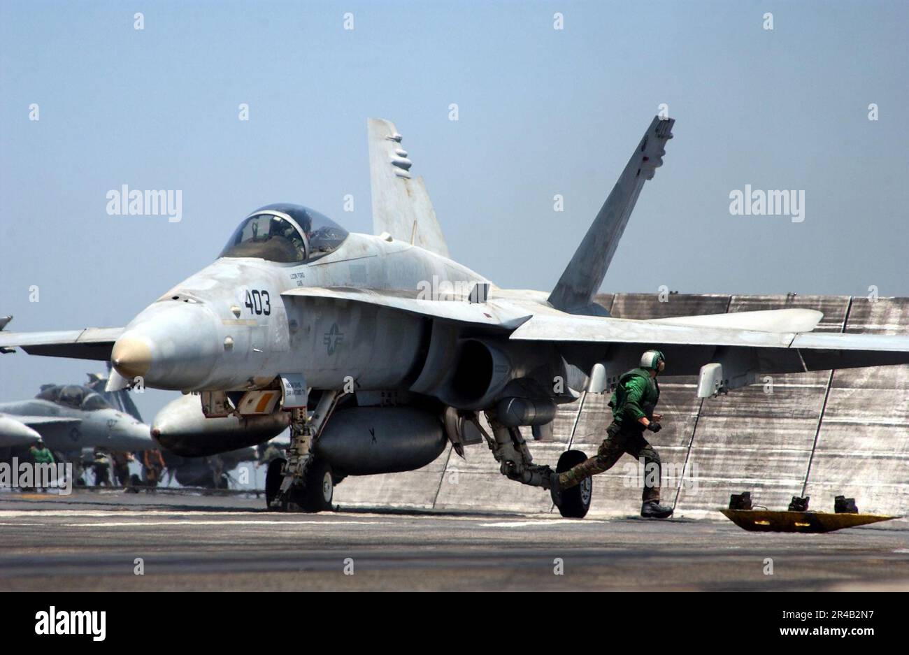 US Navy Ein Mitglied der Taillen-Katapult-Crew bewegt sich an einen sicheren Ort, nachdem er die Haltebügel in das Katapult-Shuttle eingebaut hat, um den Start einer F-A-18C Hornet vorzubereiten. Stockfoto