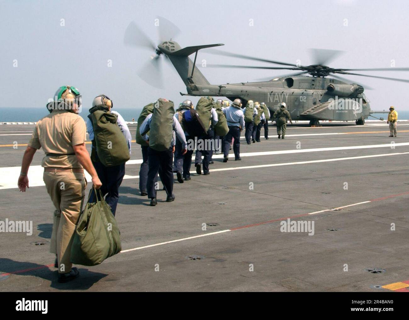US Navy, Ein US-Team Navy Aviation Boatswain's Kumpels gehen entlang des Flugdecks des Flugzeugträgers USS Harry S. Truman der Nimitz-Klasse (CVN 75) zu einem MH-53 Sea Dragon Hubschrauber, während sie sich auf den Ascheflug vorbereiten. Stockfoto