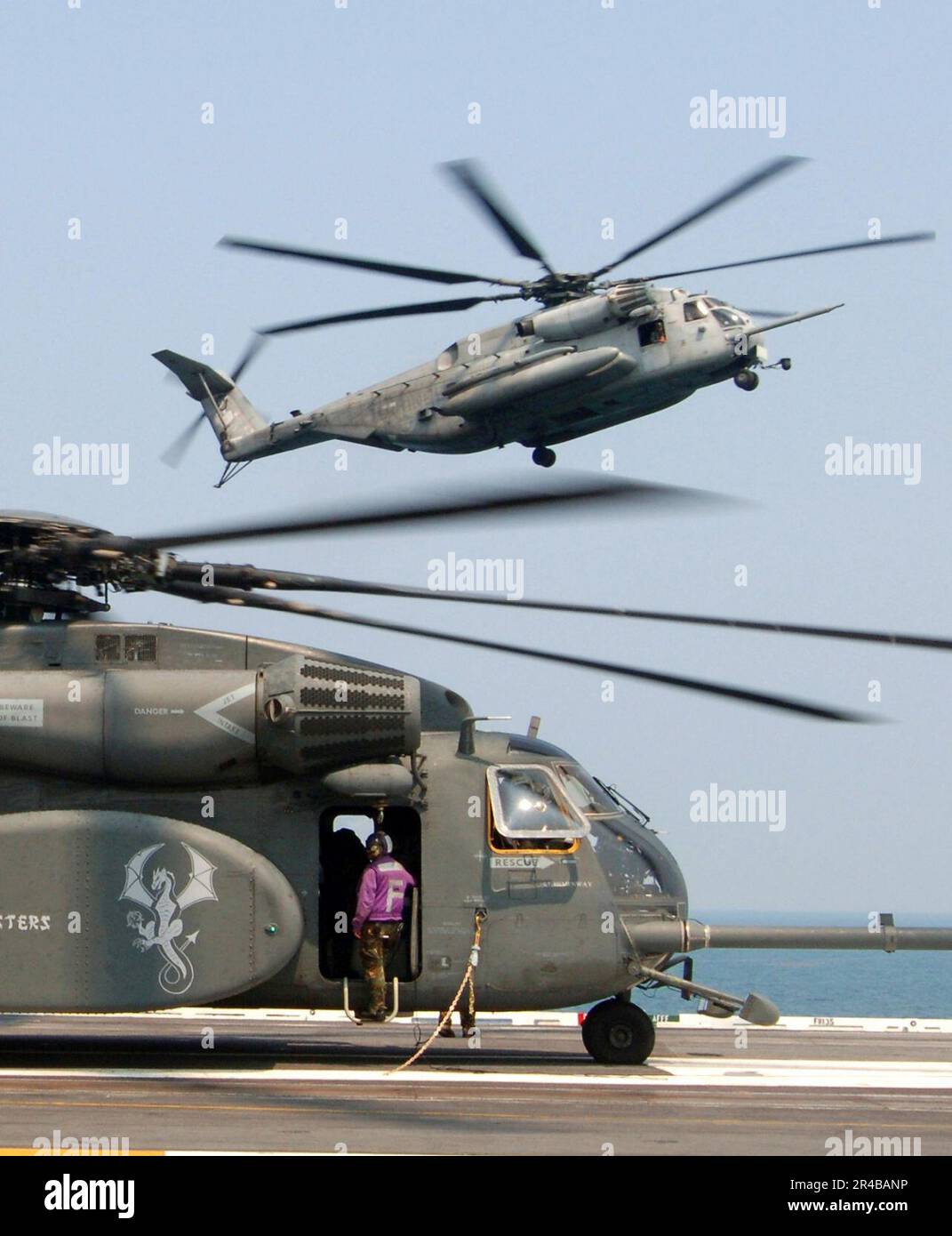 US NAVY A U.S. Marine Corps CH-53E Super-Hallion-Hubschrauber nähert sich einer Landung, während ein US-amerikanischer Der Navy MH-53 Sea Dragon Hubschrauber ruht auf dem Flugdeck des Flugzeugträgers der Nimitz-Klasse USS Harry S. T. Stockfoto