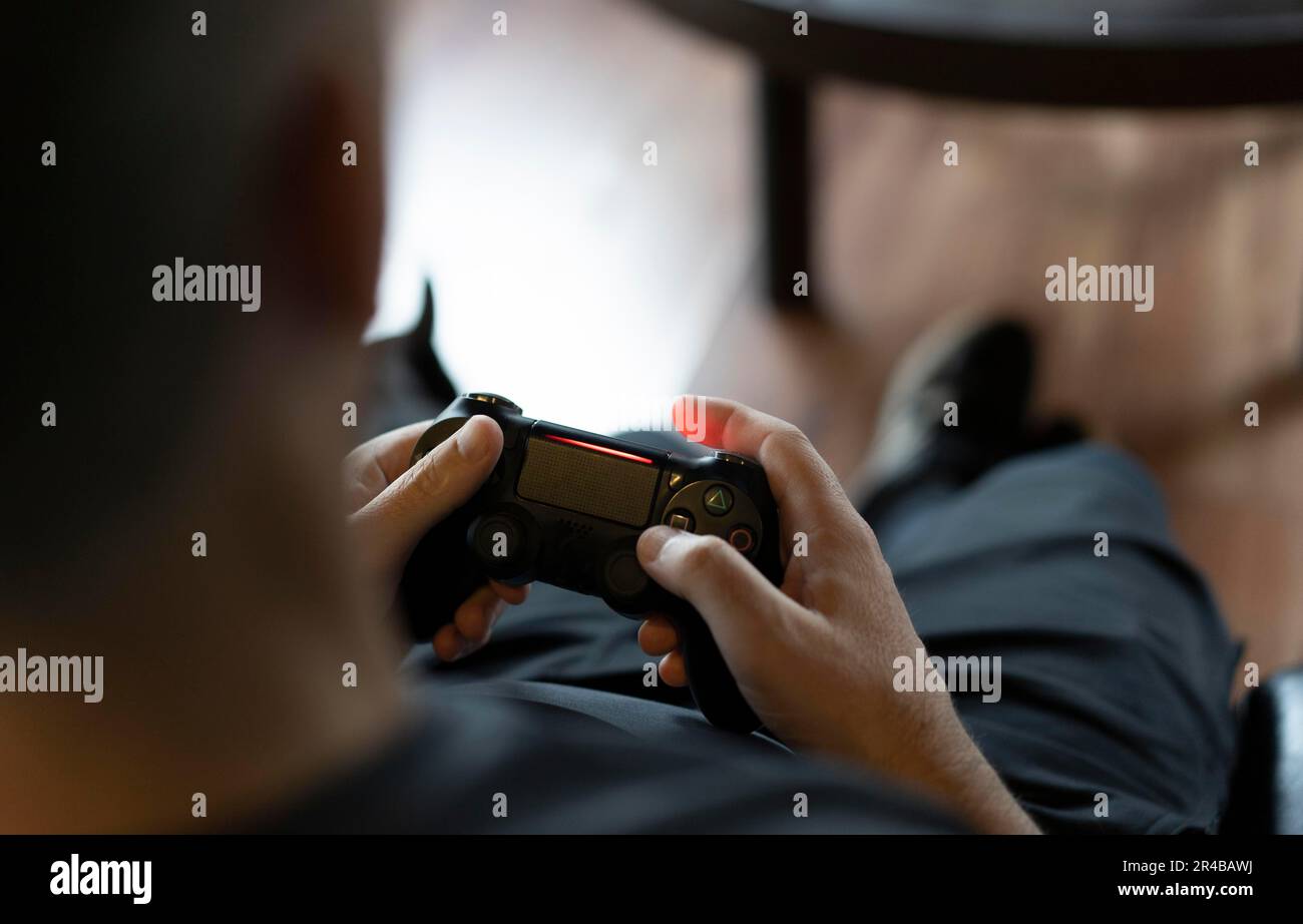 Nahaufnahme der Hände eines erwachsenen Mannes, der einen Joystick hält, während er ein Videospiel auf einer Konsole spielt. Speicherplatz kopieren Stockfoto